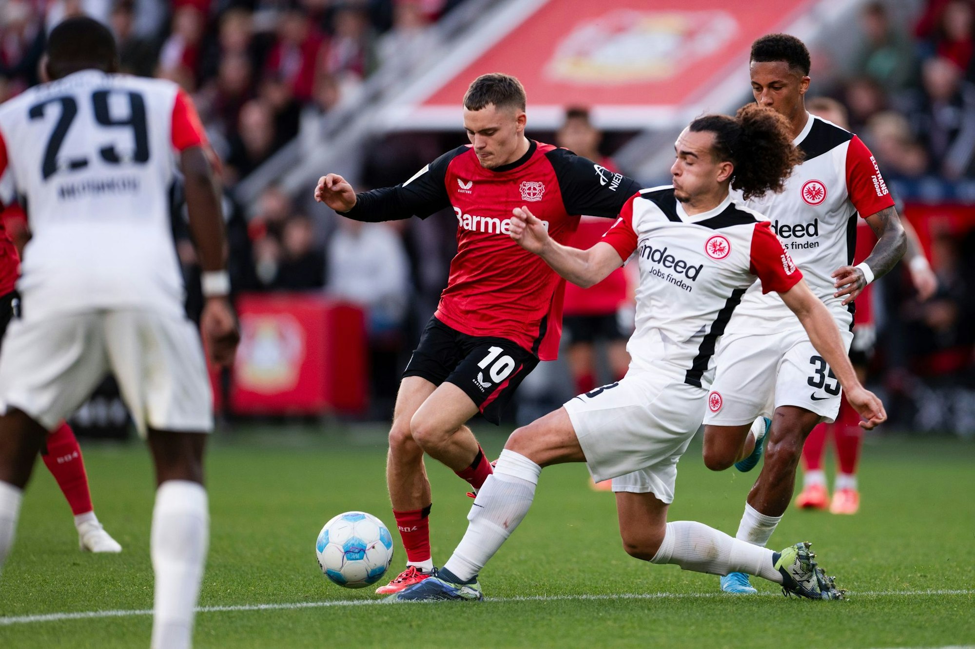 Für den Ex-Leverkusener Florian Wirtz (M) kommt es am Mittwoch zum Wiedersehen mit Eintracht Frankfurt um Arthur Theate (r). (Archivbild)