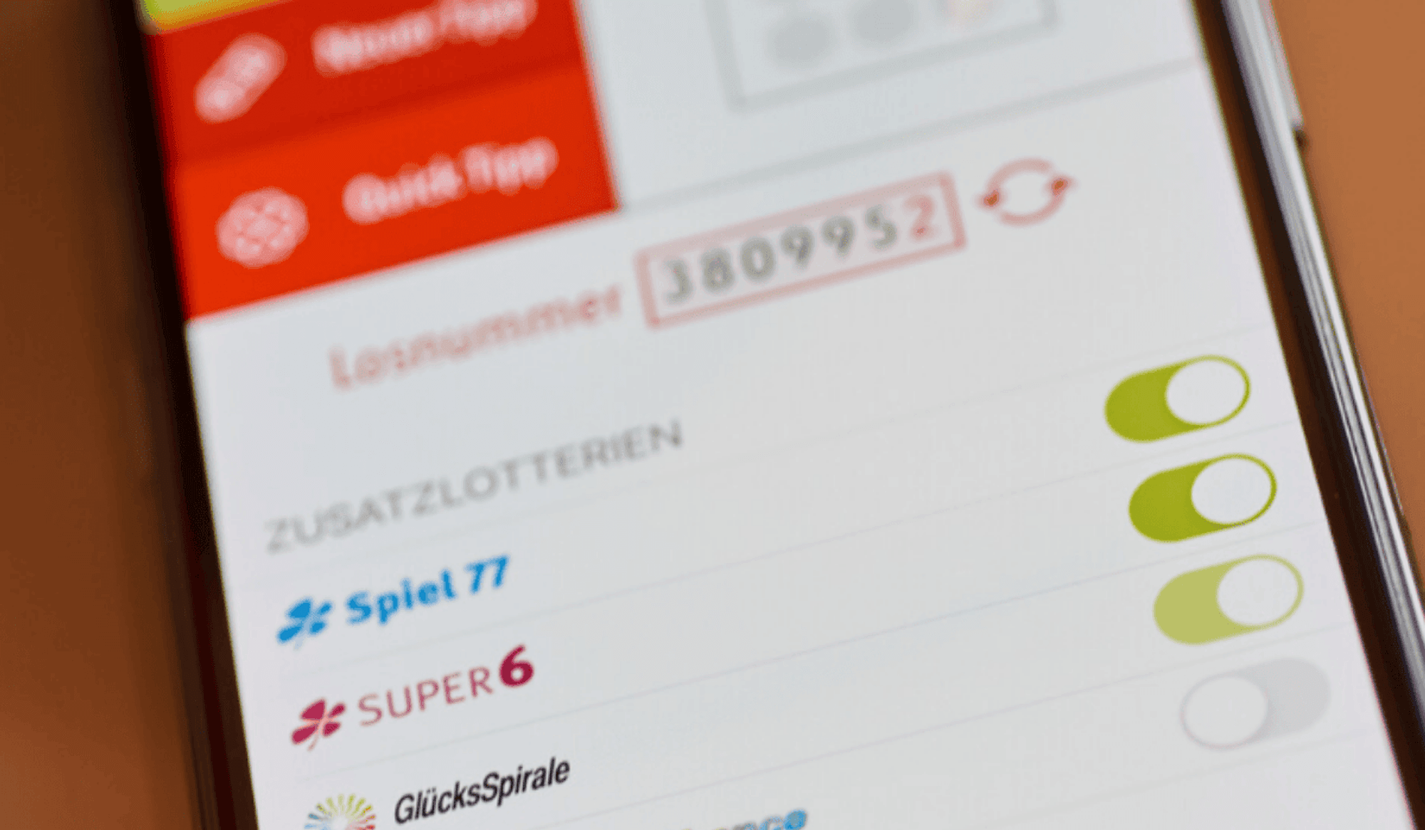 Ein Handy liegt auf einem Tisch. Auf dem Handybildschirm ist die WestLotto App zu sehen.