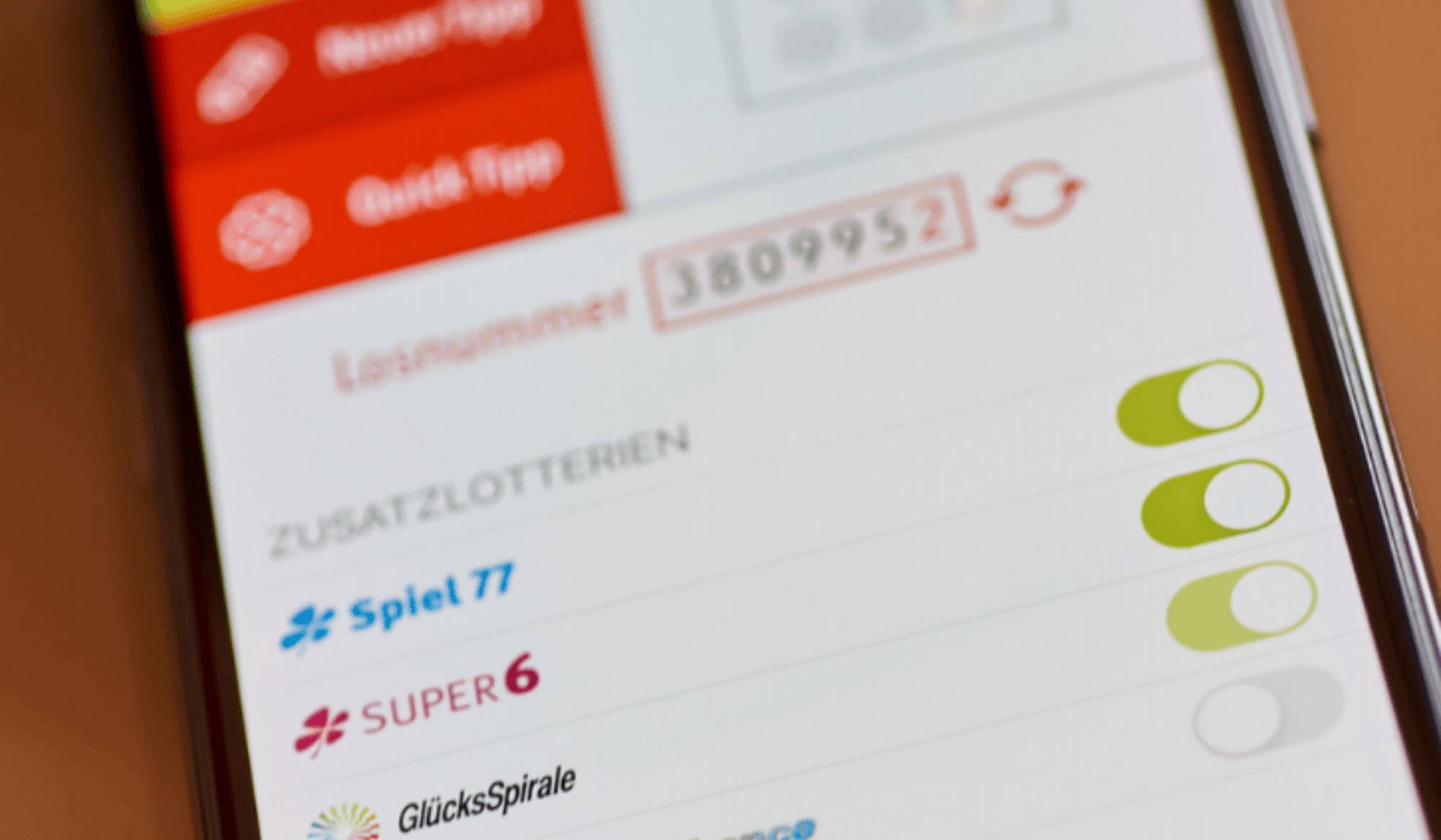 Ein Handy liegt auf einem Tisch. Auf dem Handybildschirm ist die WestLotto App zu sehen.