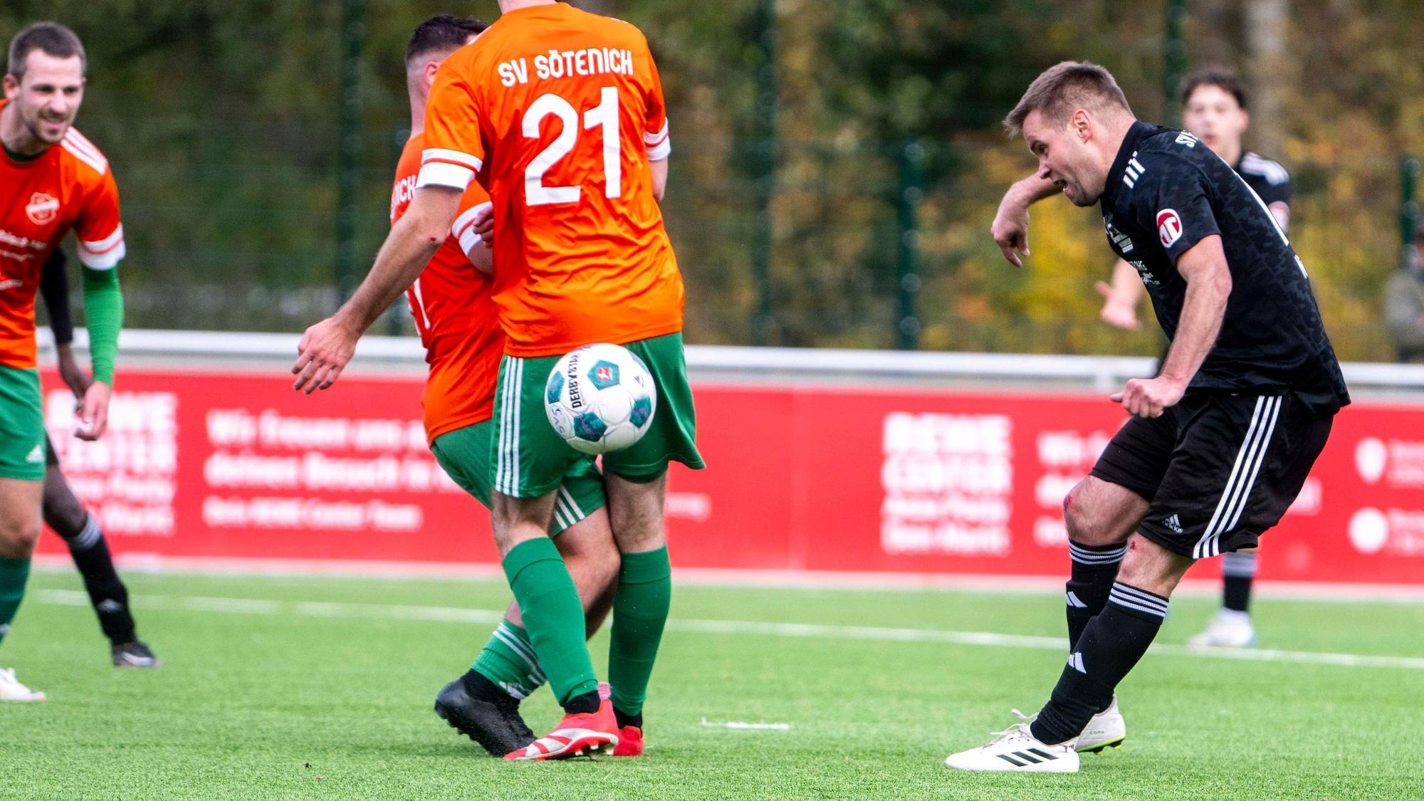 Michael Jansen spielt einen Ball hinter dem Rücken zweier Sötenicher Spieler, die sich gegenseitig behindern.
