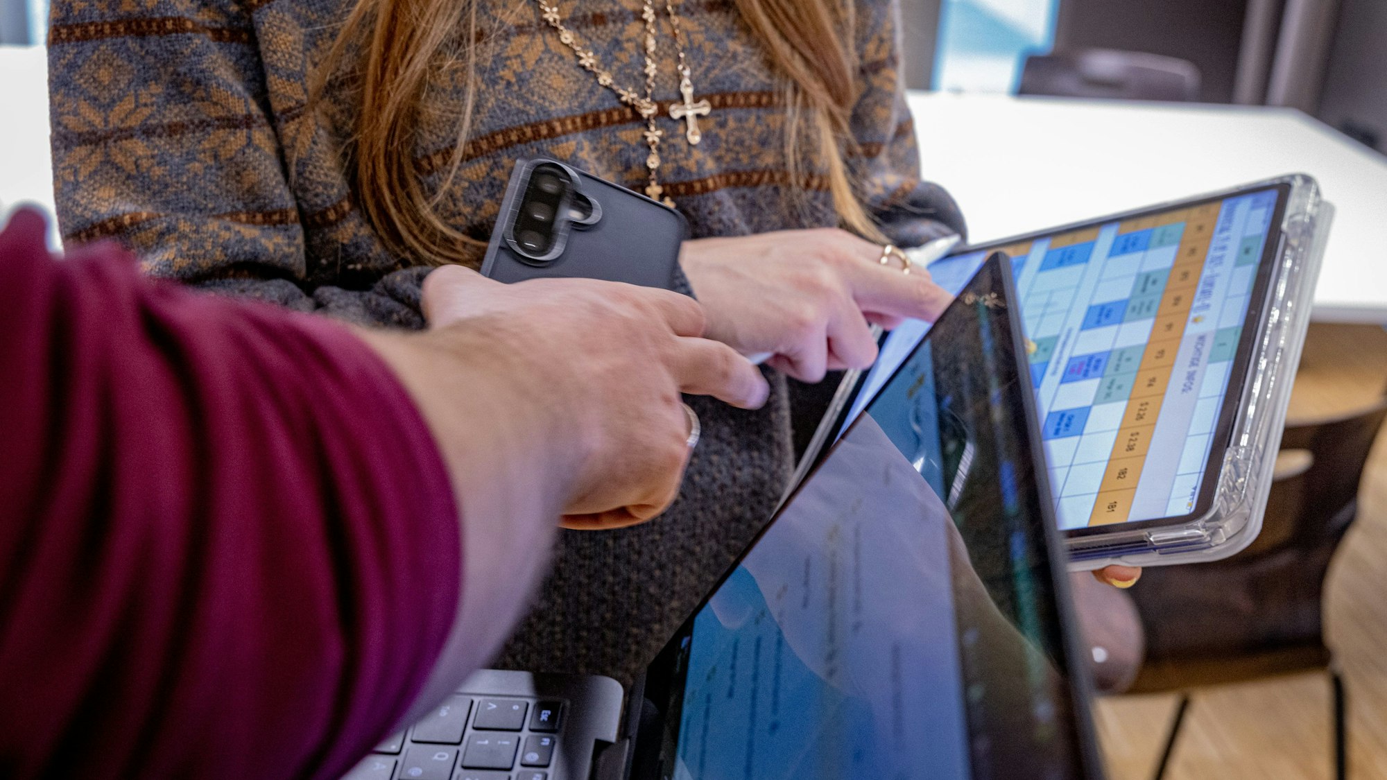 Zwei Menschen schauen auf Laptop-Bildschirme mit Plänen.