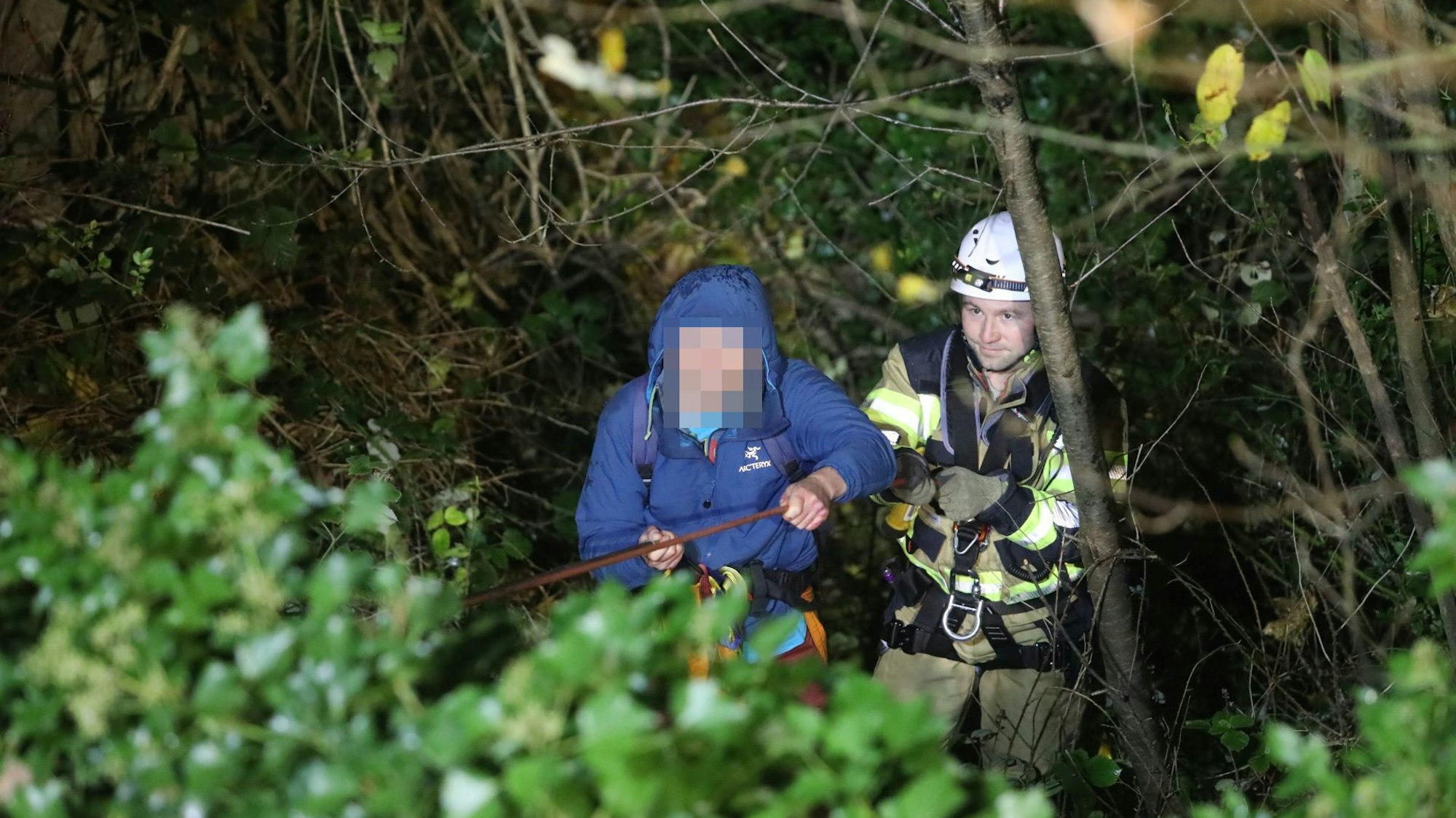Ein Mann in blauer Outdoor-Jacke und ein Feuerwehrmann.