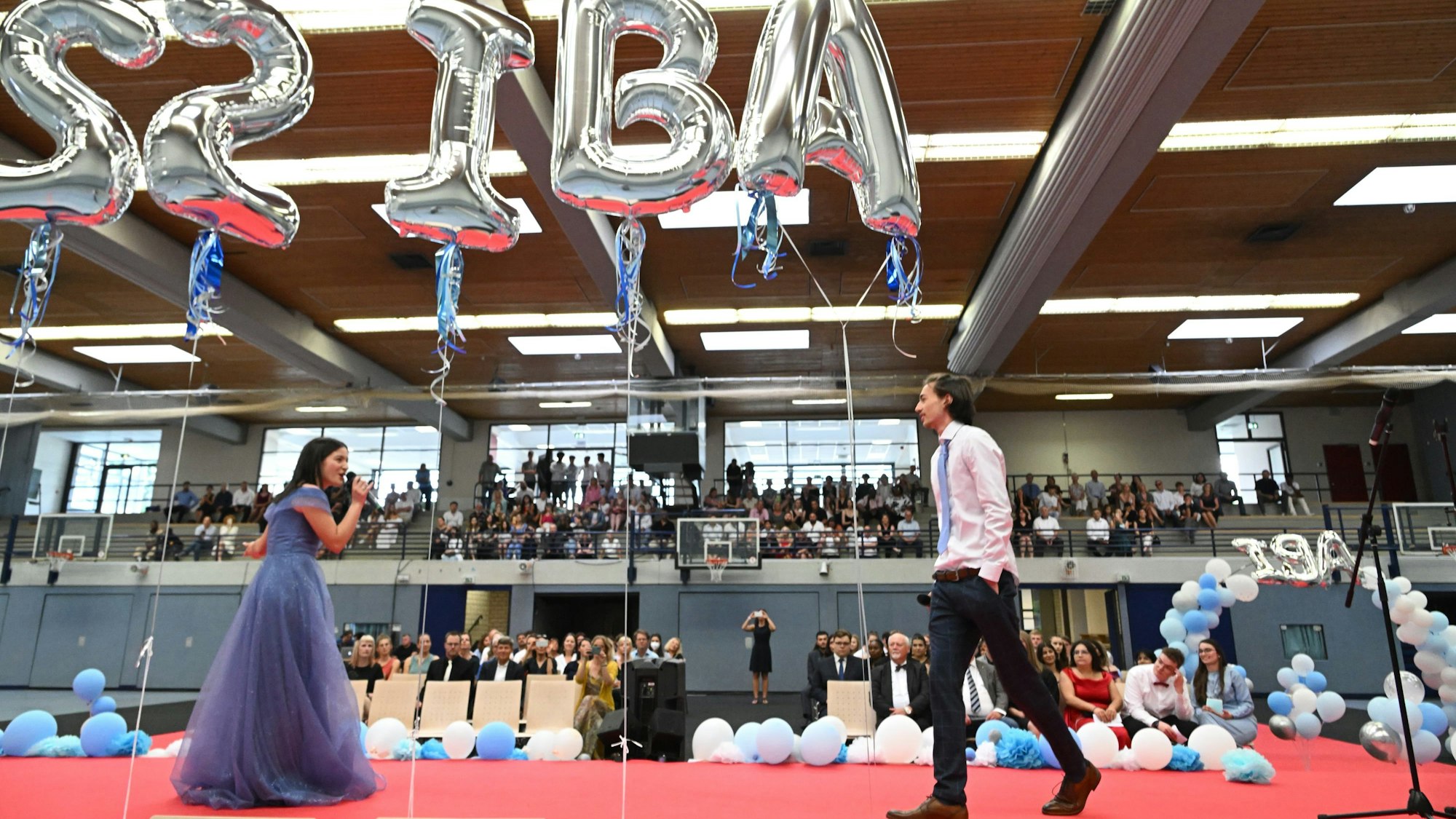 Auf der Bühne stehen zwei Abiturienten.