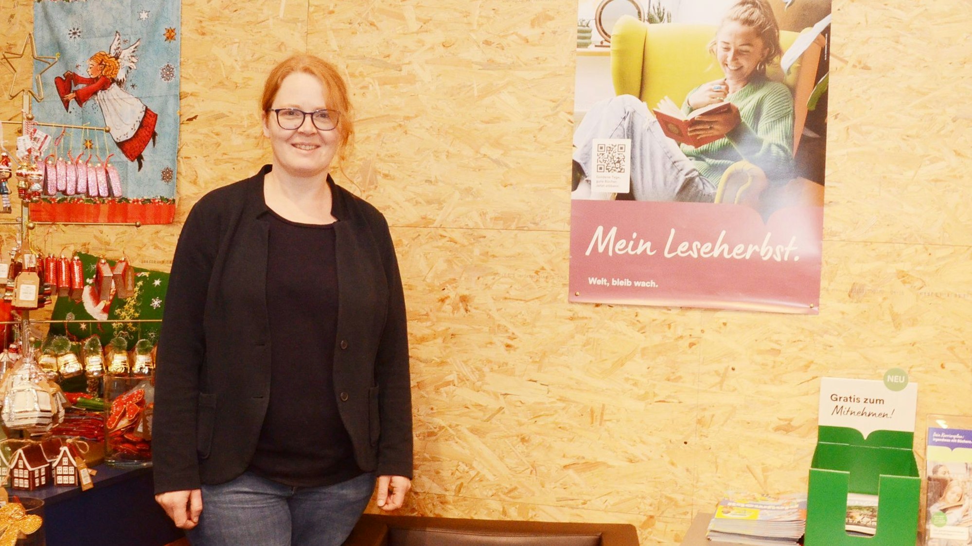 Eine junge Frau mit roten Haaren steht vor einer Wand aus OSB-Holzplatten