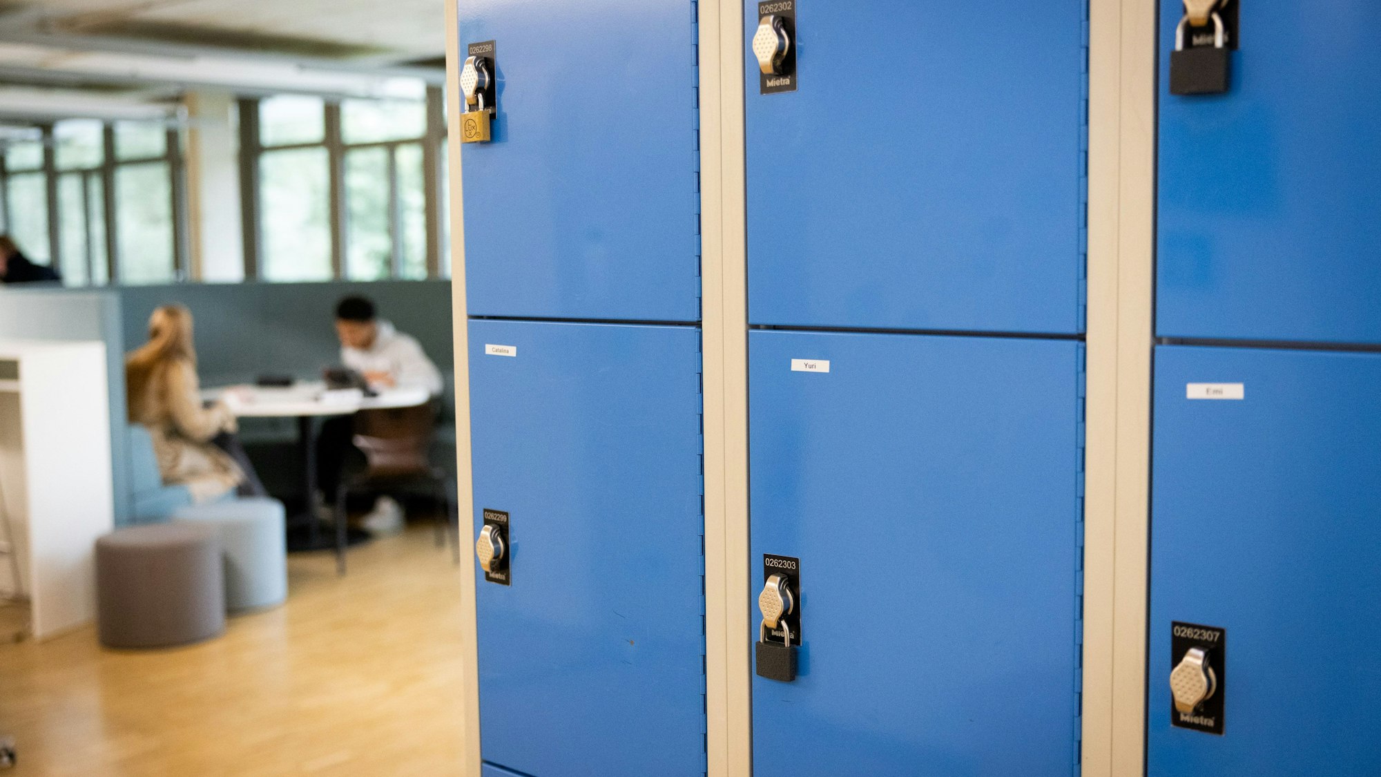 Spinde für Materialien und Lernende, die an einem Tisch sitzen,im Hintergrund.