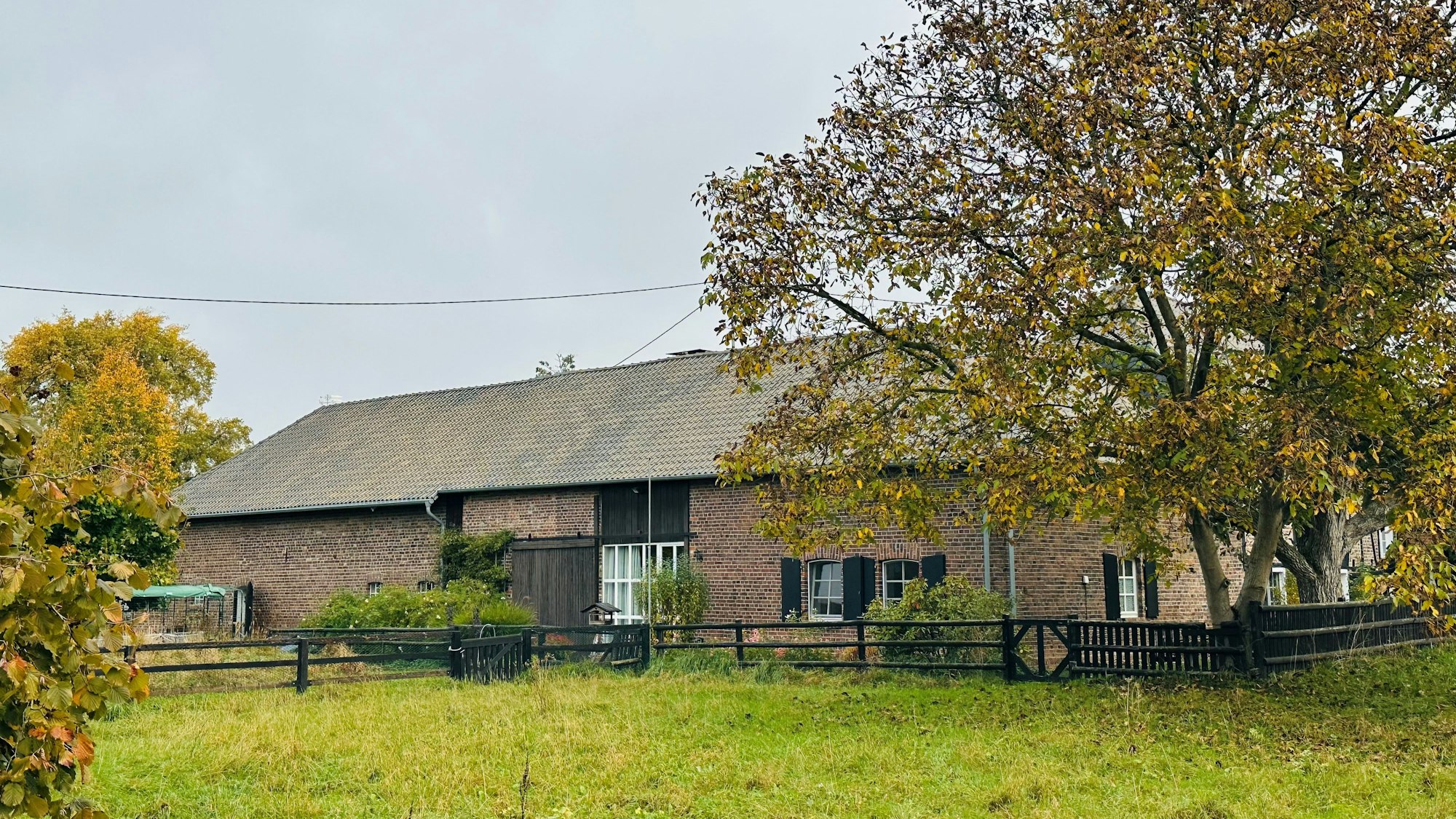 Zu sehen ist eine Hofanlage vor, davor eine Wiese.