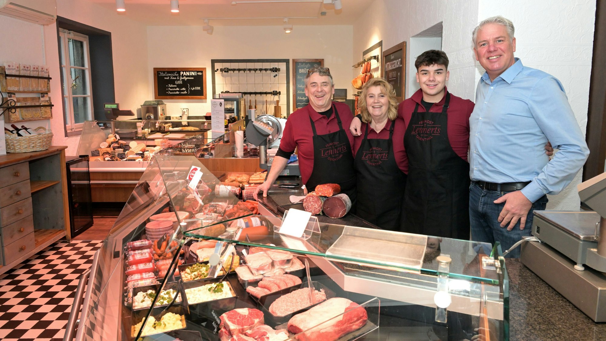 Vier Menschen stehen hinter der Theke einer Metzgerei.
