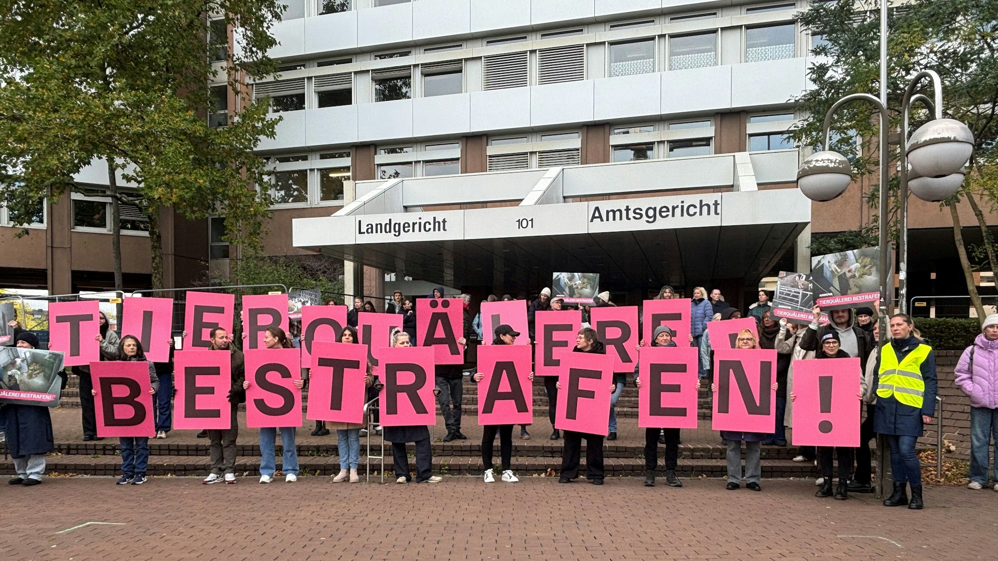 Das Bild zeigt mehrere Demonstranten vor dem Gerichtsgebäude.
