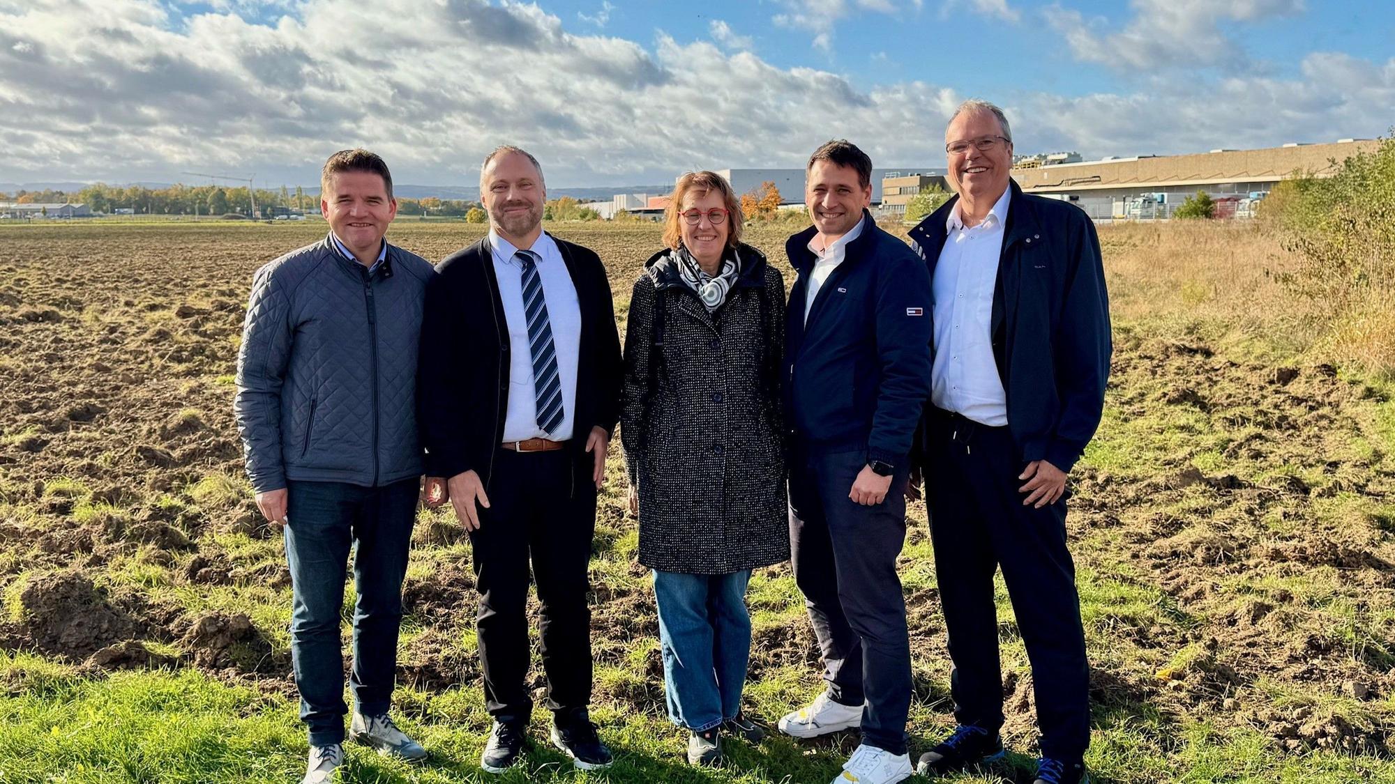 Eine Gruppe Politiker und Unternehmer steht vor dem Feld, auf dem die neue Firma entstehen soll.