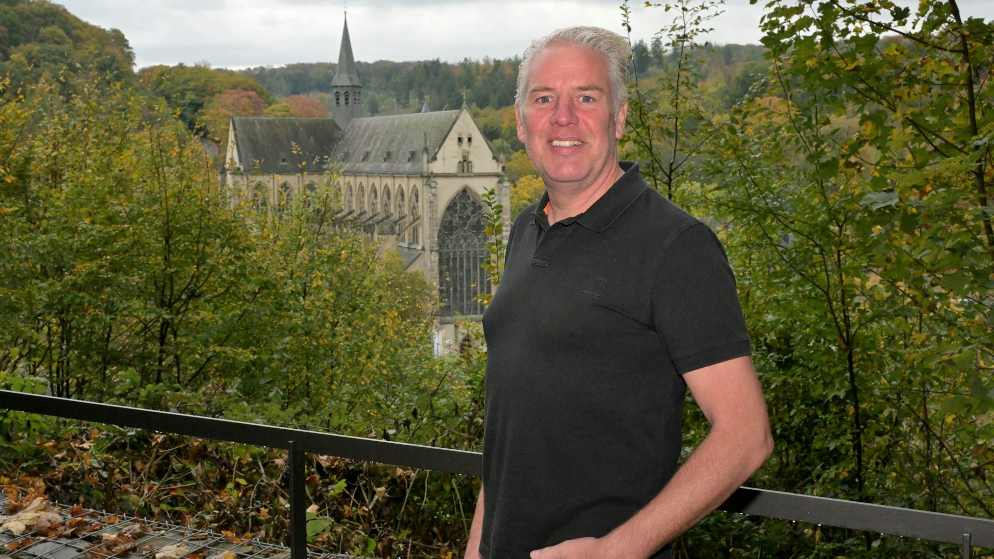 Ein Mann im schwarzen Polohemd steht an einem Aussichtspunkt mit Blick auf den Altenberger Dom.