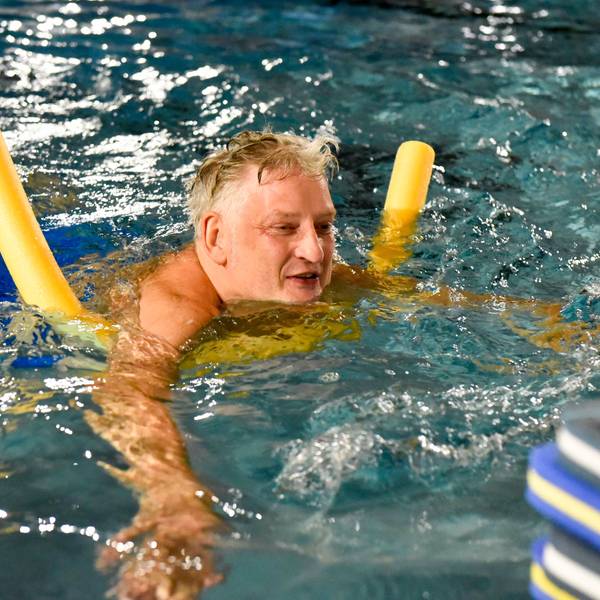 Das Bild zeigt den Mann mit einer Schwimmnudel im Becken.