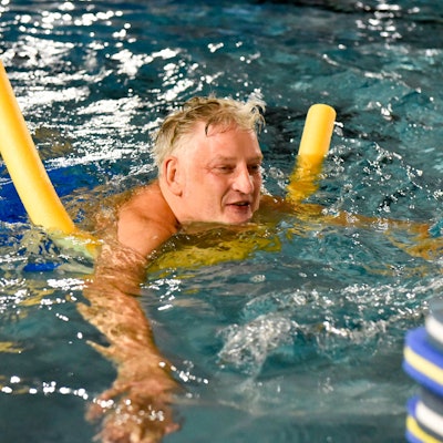 Das Bild zeigt den Mann mit einer Schwimmnudel im Becken.