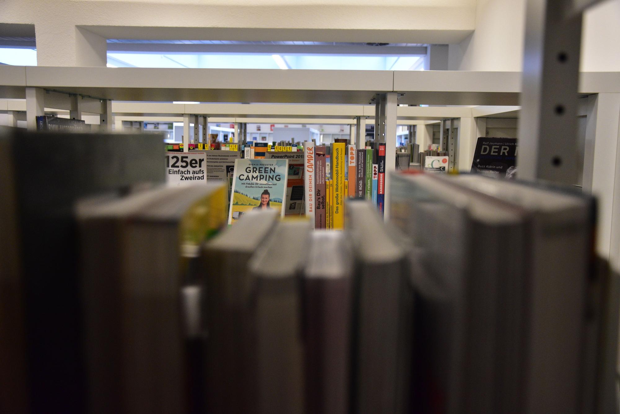 Blick durch gefüllte Regale in einer Bibliothek.
