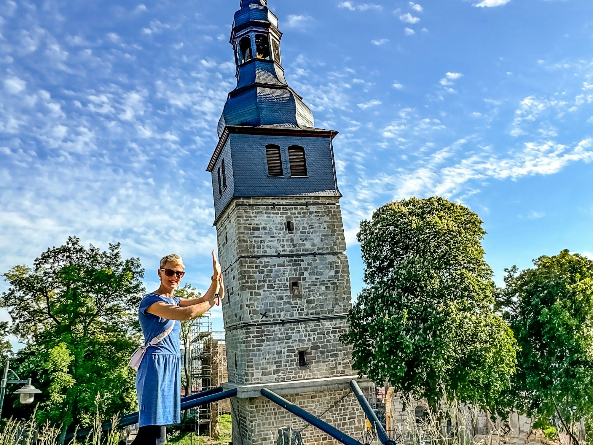 Ein Foto ist so aufgenommen, dass es aussieht, als halte eine Person den schiefen Turm von Bad Frankenhausen fest.