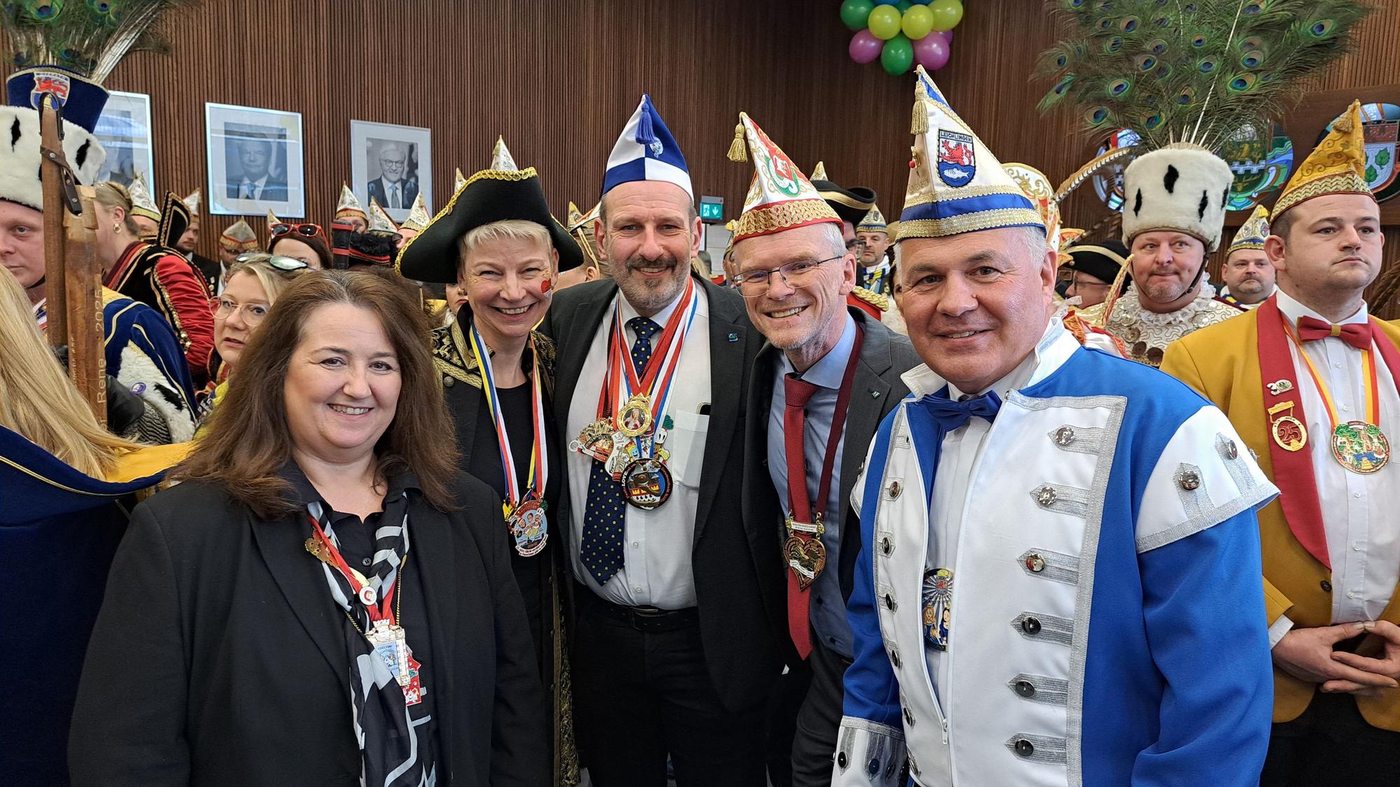 Arm in Arm stehen fünf Bürgermeister inmitten von Karnevalisten.