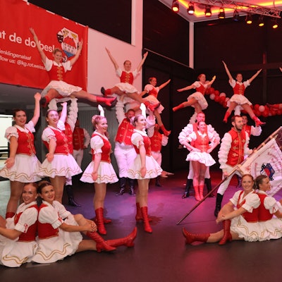Im sitzen und im stehen, präsentiert sich eine Tanzgruppe auf der Bühne.