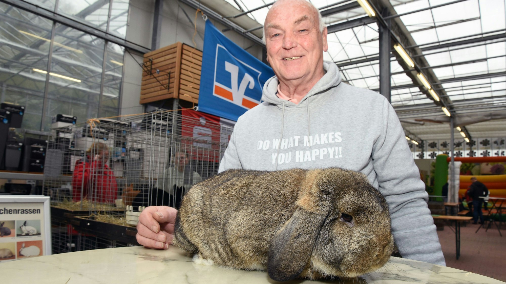 Ein Mann steht an einem Tisch, auf dem ein großes Kaninchen sitzt.