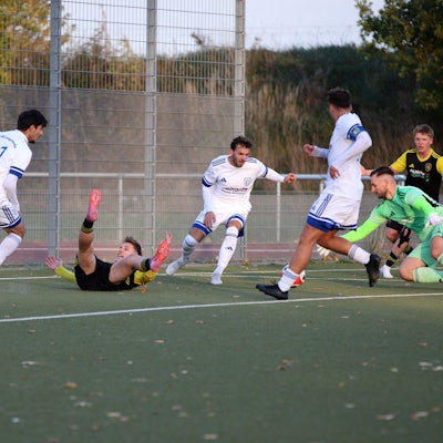 Erftstadt-Lechenichs Spieler Jan-Philipp Schmitz liegt auf dem Rücken und beschwert sich mit ausgestreckten Armen. Der Ball liegt zwischen Torwart und einem Verteidiger von Langerwehe.