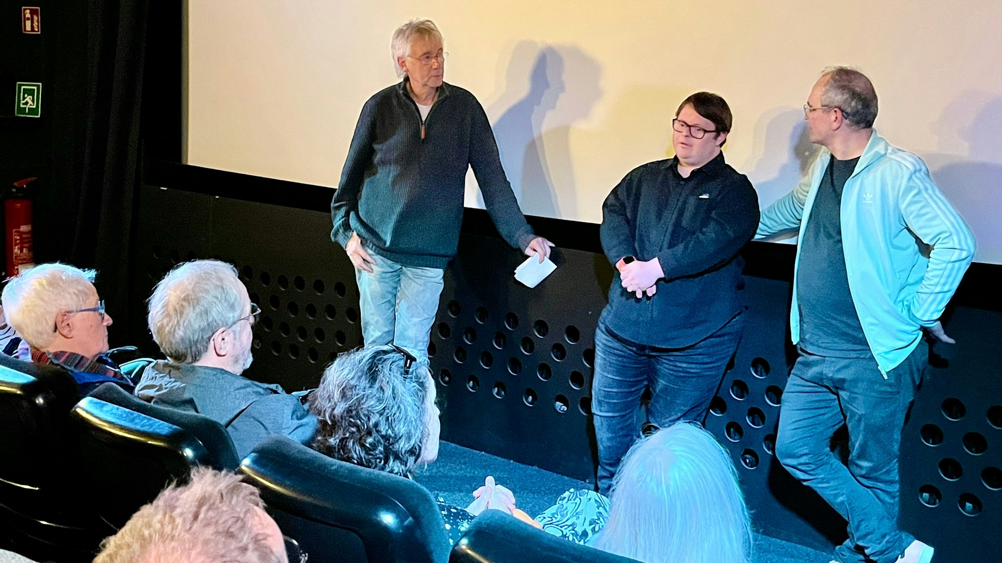 Zu sehen sind Hans-Jörg Blondiau, Clemente Fernandez-Gil und Nico Randel vor der Leinwand des Kinos.