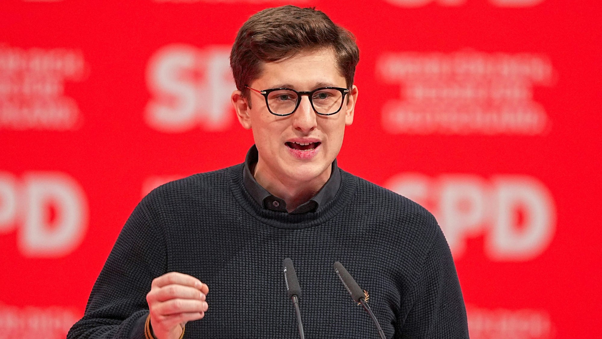 Vor einer roten SPD-Plakatwand spricht Juso-Chef Philipp Türmer.