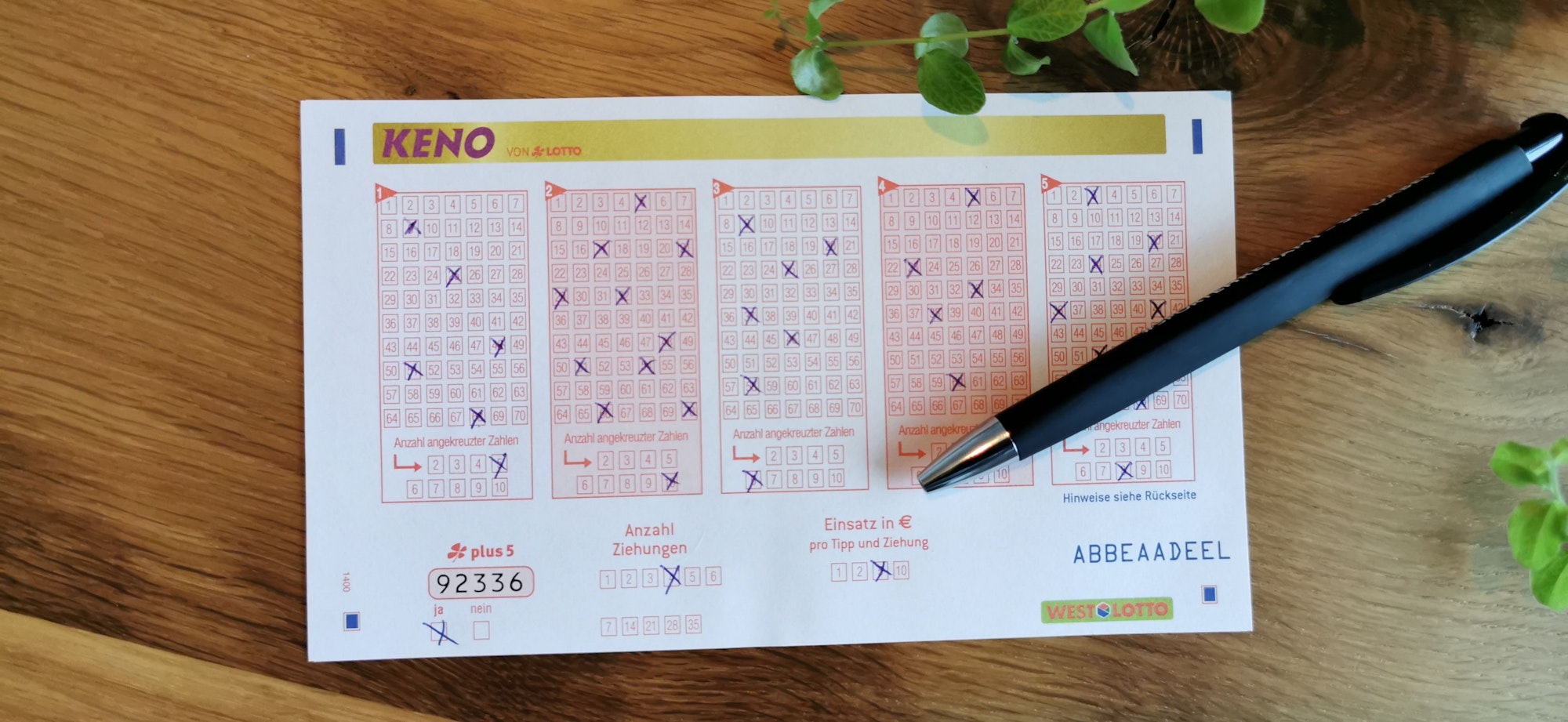 Auf einem Holztisch liegt ein Zettel, auf dem für das Gewinnspiel KENO Zahlen angekreuzt wurden.