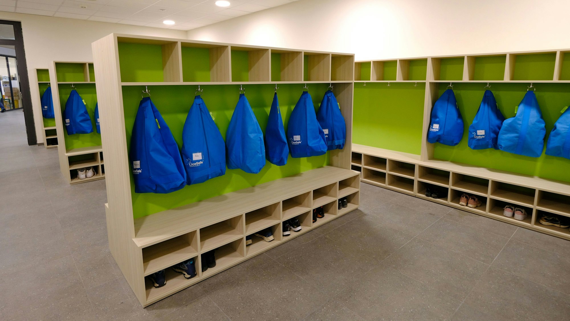 Im Garderobenraum der Gemeinschaftsgrundschule Firmenich-Obergartzem hängen blaue Kleidersäcke an den Haken.