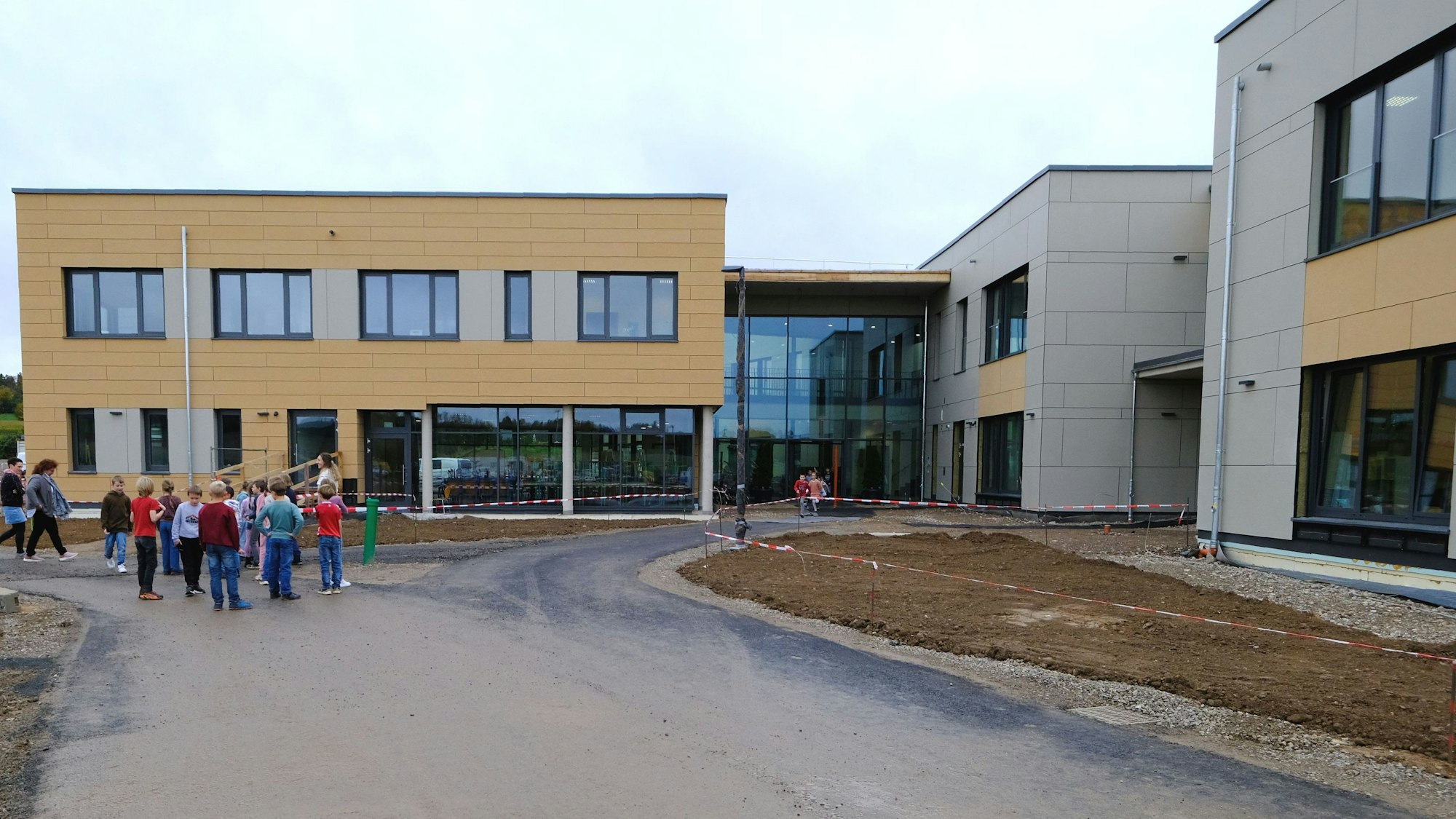 Eine Gruppe von Schulkindern steht vor dem Gebäude der Gemeinschaftsgrundschule Firmenich-Obergartzem.