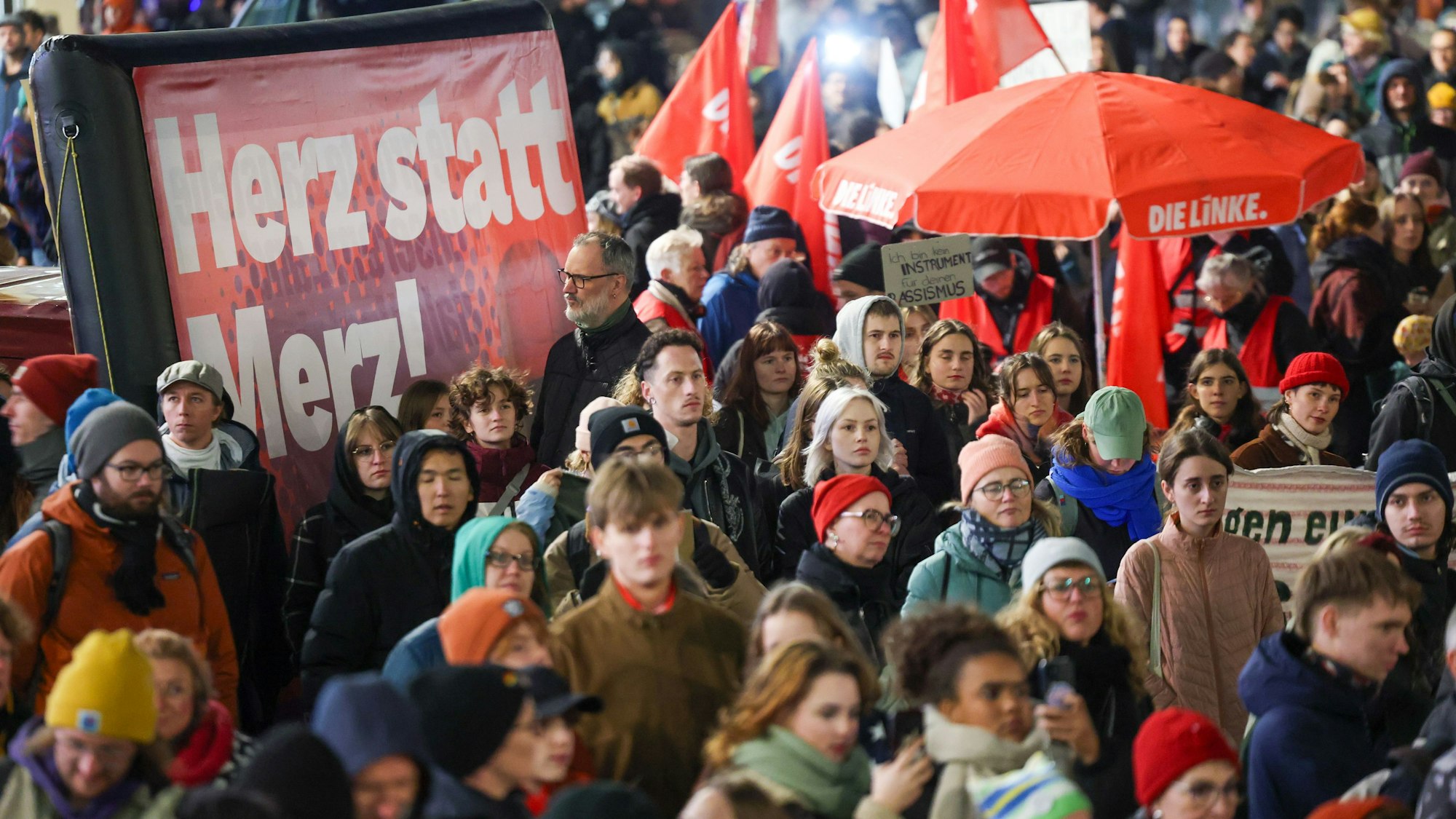 Teilnehmer einer Demonstration «Das Stadtbild bleibt bunt» stehen neben einem Plakat mit der Aufschrift «Herz statt Merz!» auf dem Marktplatz.