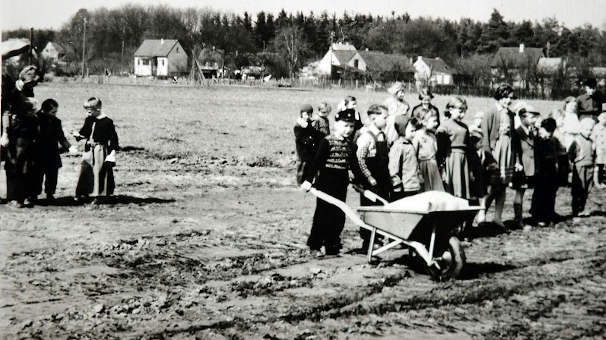 Ein historisches Foto, Kinder mit einer Schubkarre auf einem Baugrundstück.