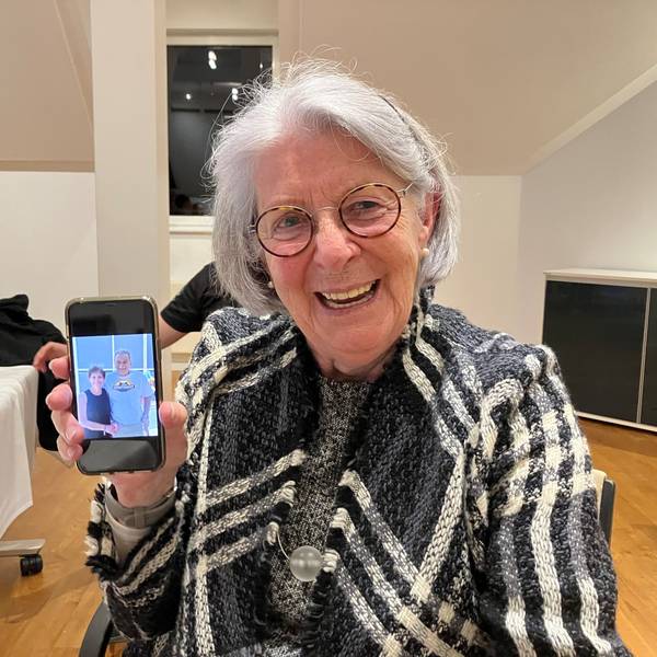 Eine ältere Dame zeigt ein Foto mit zwei Personen auf ihrem Handy.