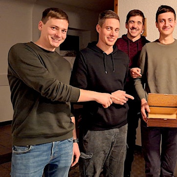 Sechs junge Männer zeigen auf die Sammelkiste, mit der sie durchs Dorf ziehen.