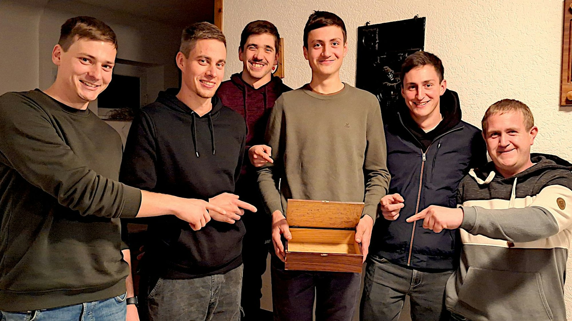 Sechs junge Männer zeigen auf die Sammelkiste, mit der sie durchs Dorf ziehen.