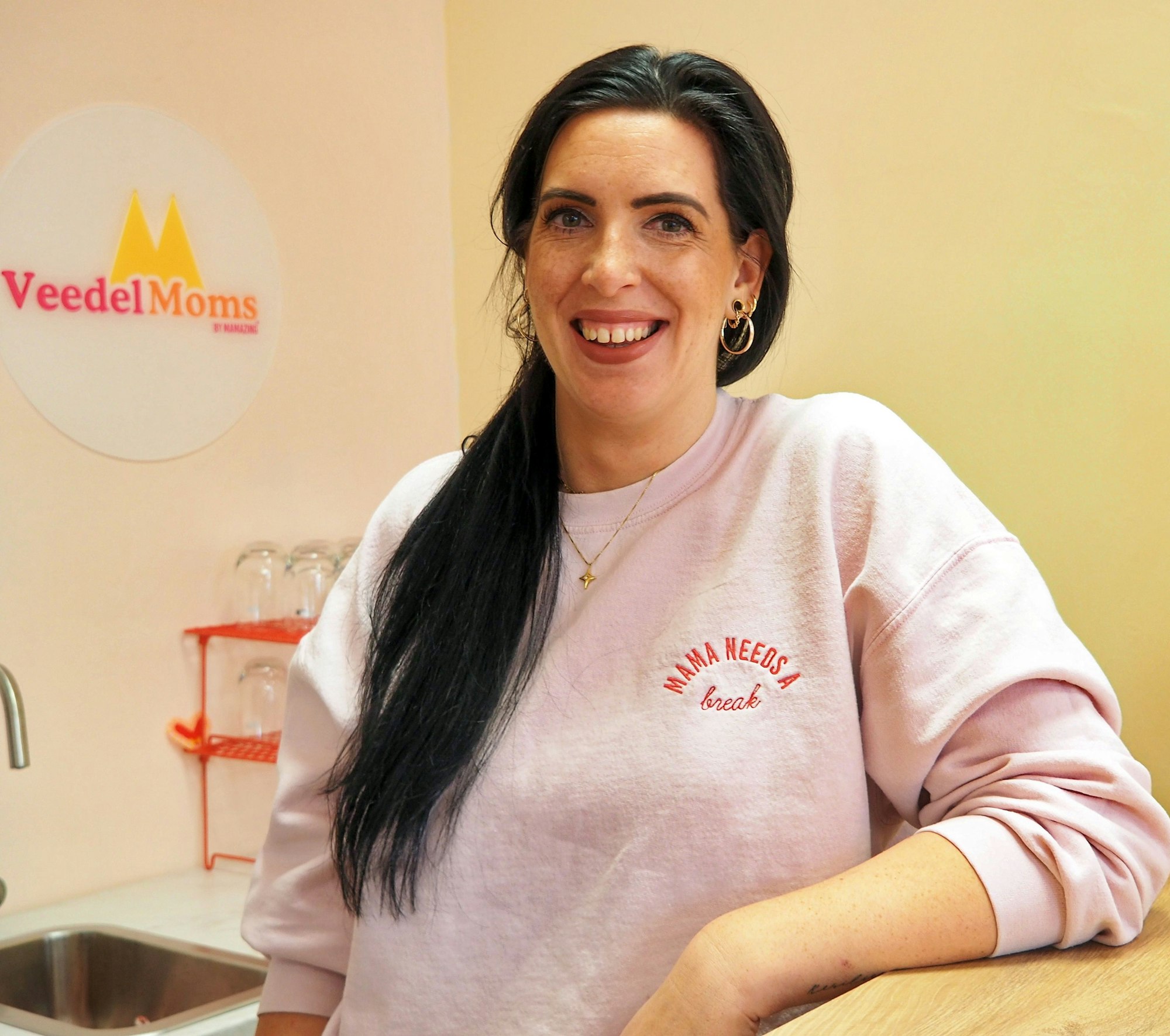 Eine Frau mit langem dunklen Zopf lehnt an einer Theke.