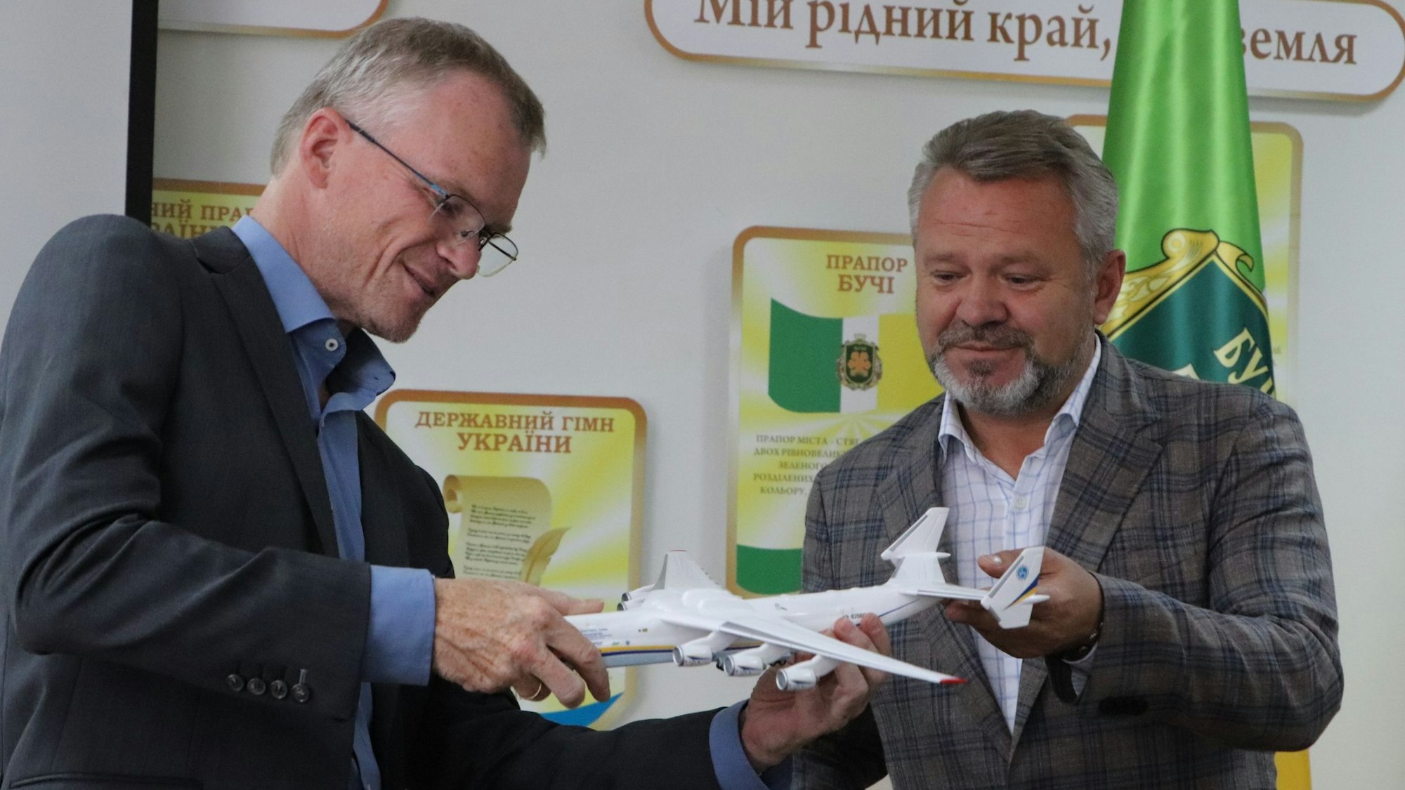 Der scheidende Bürgermeister von Bergisch Gladbach, Frank Stein, und der Bürgermeister der Stadt Butscha, Anatolii Fedoruk, stehen nebeneinander und halten gemeinsam ein Modellflugzeug. Beide lächeln leicht.