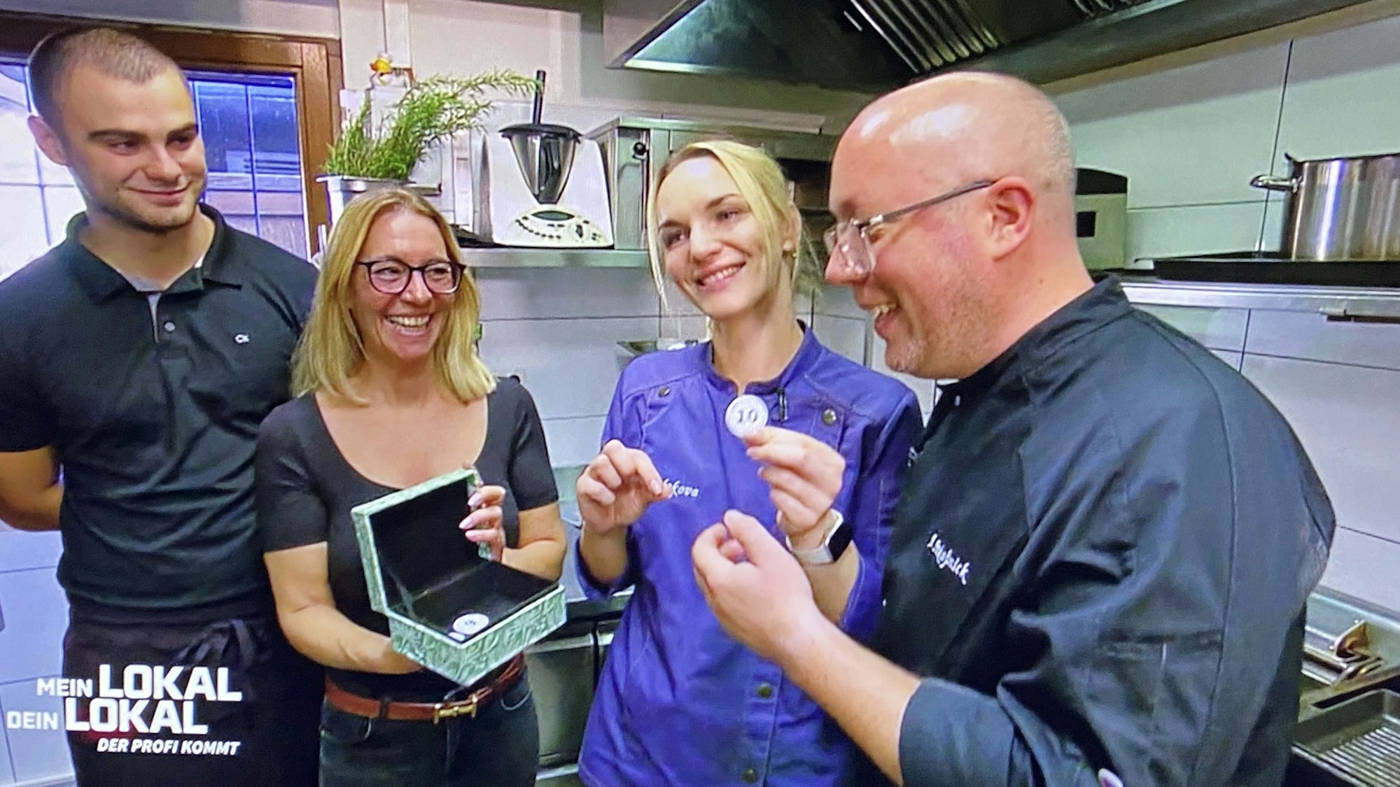 Zu sehen sind zwei Männer und zwei Frauen in einer Küche.