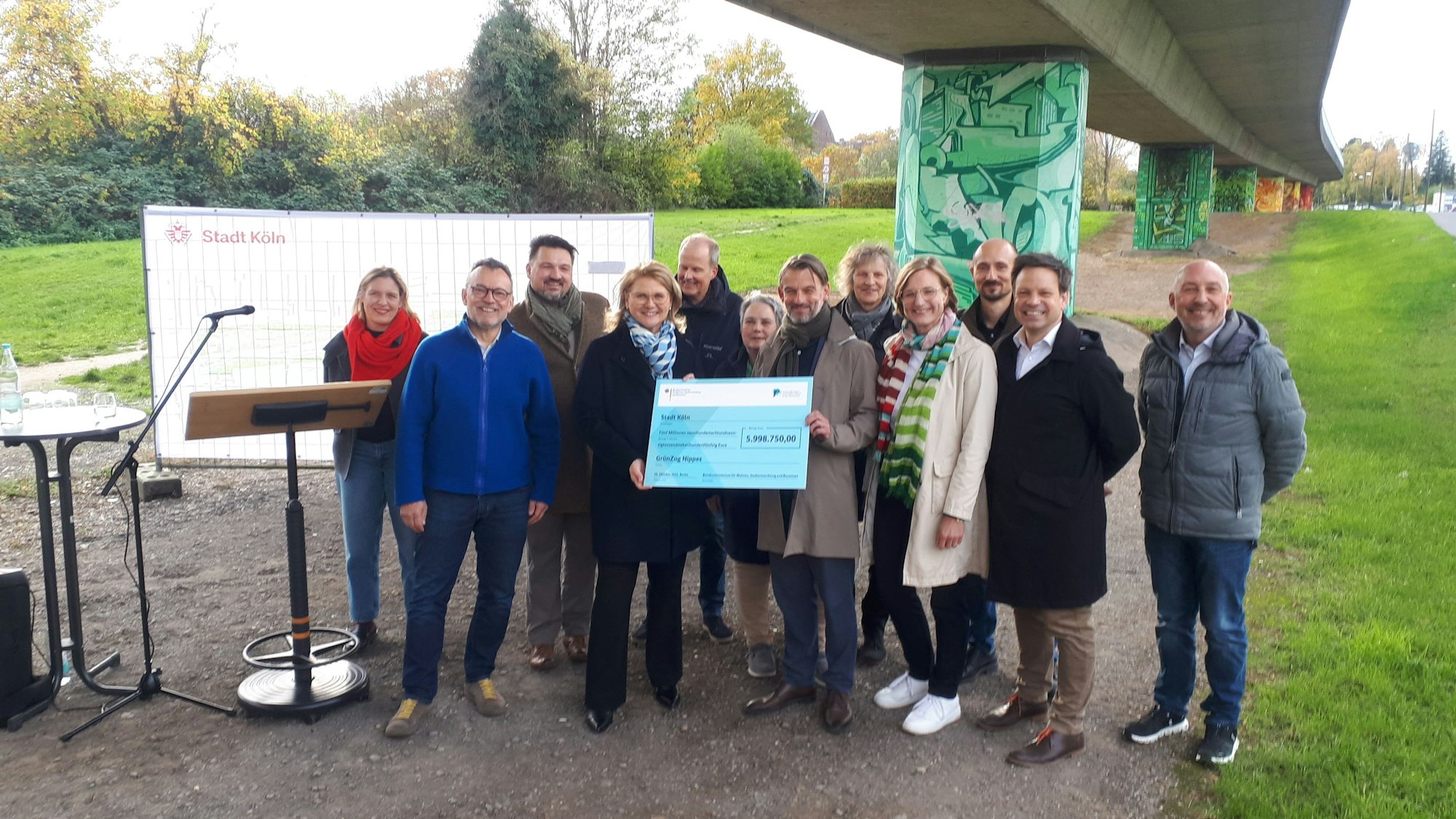 Sabine Poschmann, Parlamentarische Staatssekretärin im Bundes-Bauministerium, übergibt den symbolischen Scheck an William Wolfgramm, Klima- und Umweltdezernent.