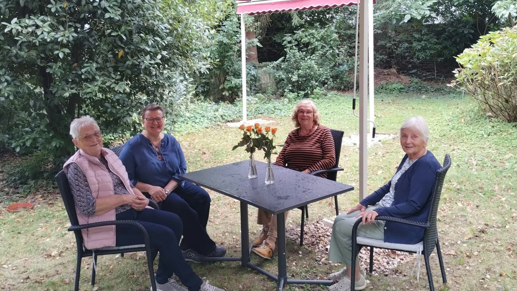 Vier Frauen sitzen im Garten um einen Tisch. Die Rundschau-Altenhilfe hat den Diakoniepunkt Nippes dabei unterstützt, Gartenmöbel anzuschaffen.