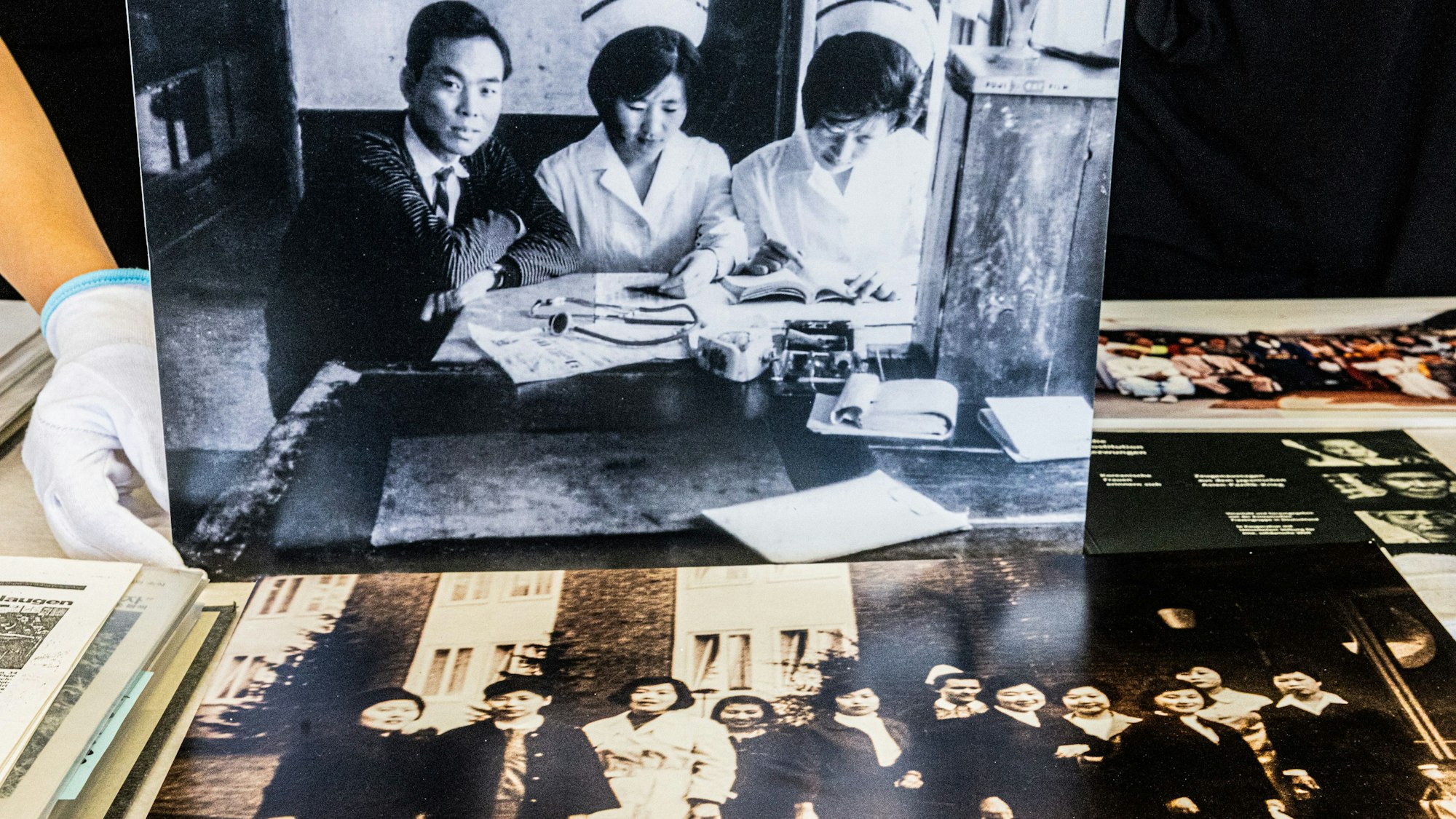 Die historischen Fotografien zeigen koreanische Pflegekräfte in Korea und in Deutschland. Frau An-Mäckler als examinierte koreanische Krankenschwester bei der Arbeit in Korea und koreanische Pflegekräfte nach ihrer Ankunft in Deutschland.