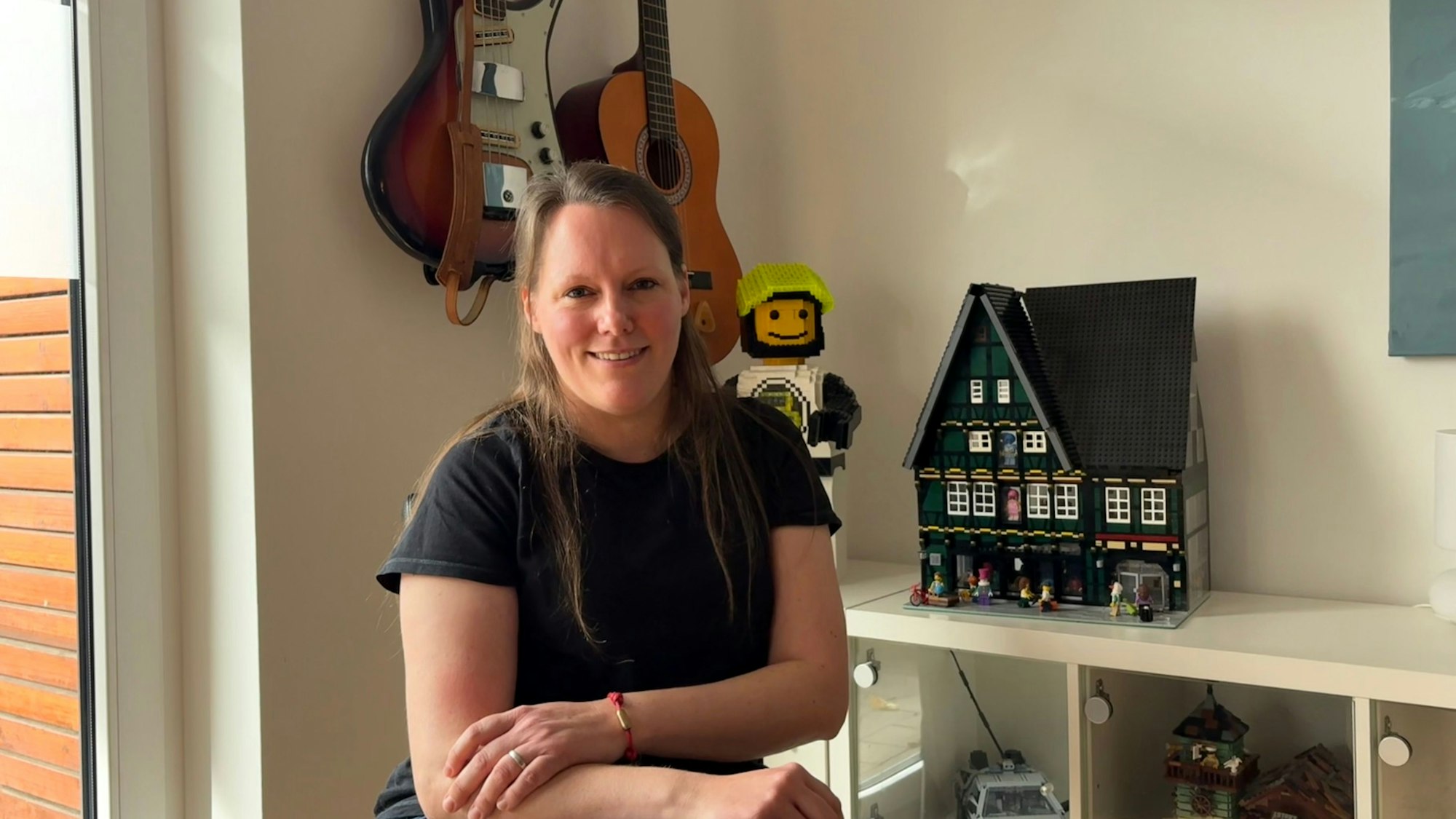 Juliane Pilster aus Köln baut für das Lego House: Im Hintergrund links die echte Bassgitarre, die sie nachgebaut hat, sowie das Haus aus ihrer Heimatstadt.
