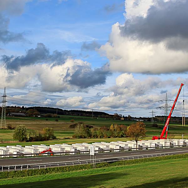 Auf 300 Metern wird an der B51 ein großes Batteriespeicherwerk gebaut. Ein roter Kran setzt die Elemente auf die Fundamente.