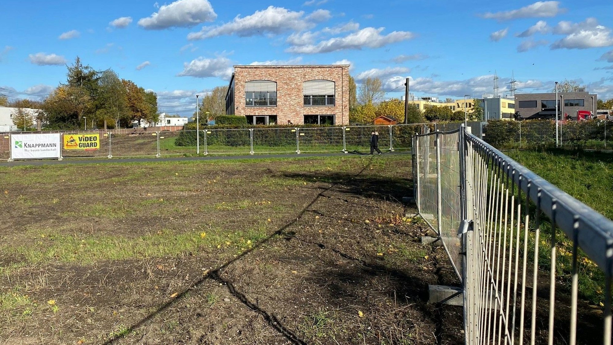 Zu sehen ist eine umzäunte Brachfläche.