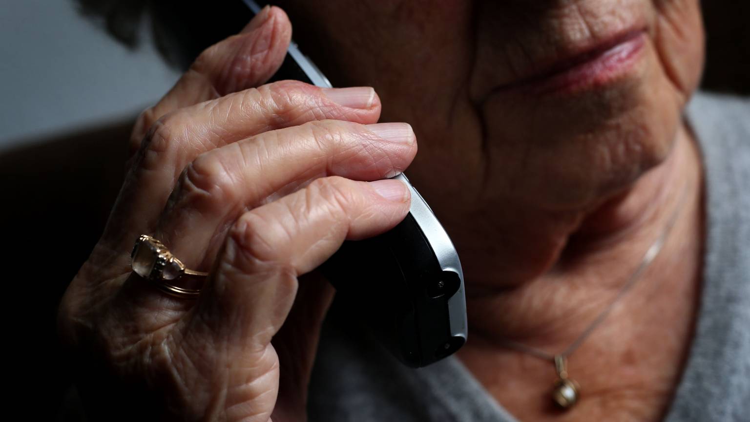 Eine ältere Frau telefoniert mit einem schnurlosen Festnetztelefon.