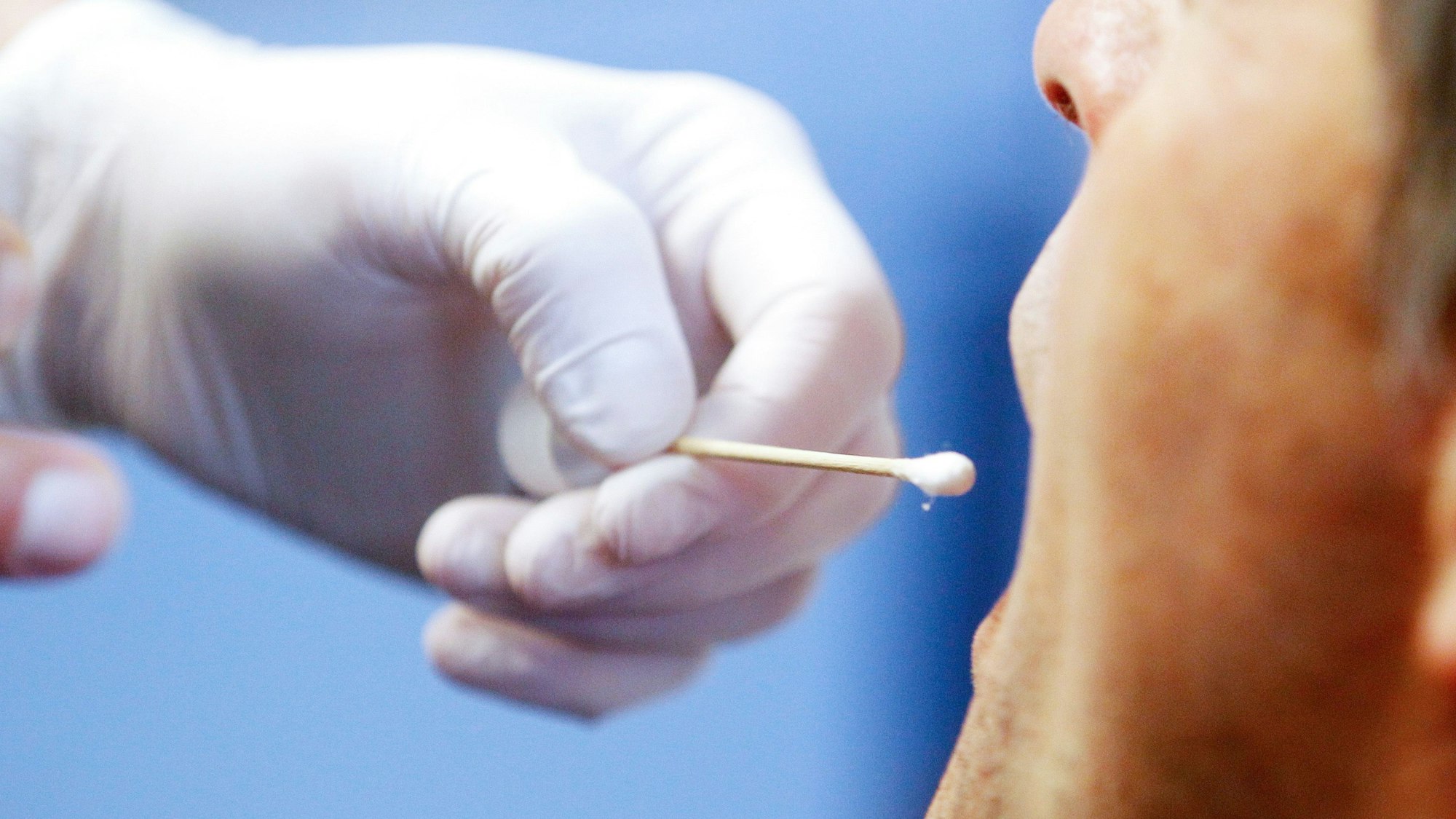 Die Polizei führt einen DNA-Speicheltest bei einem Mann (Polizist) in einem Mordfall durch.