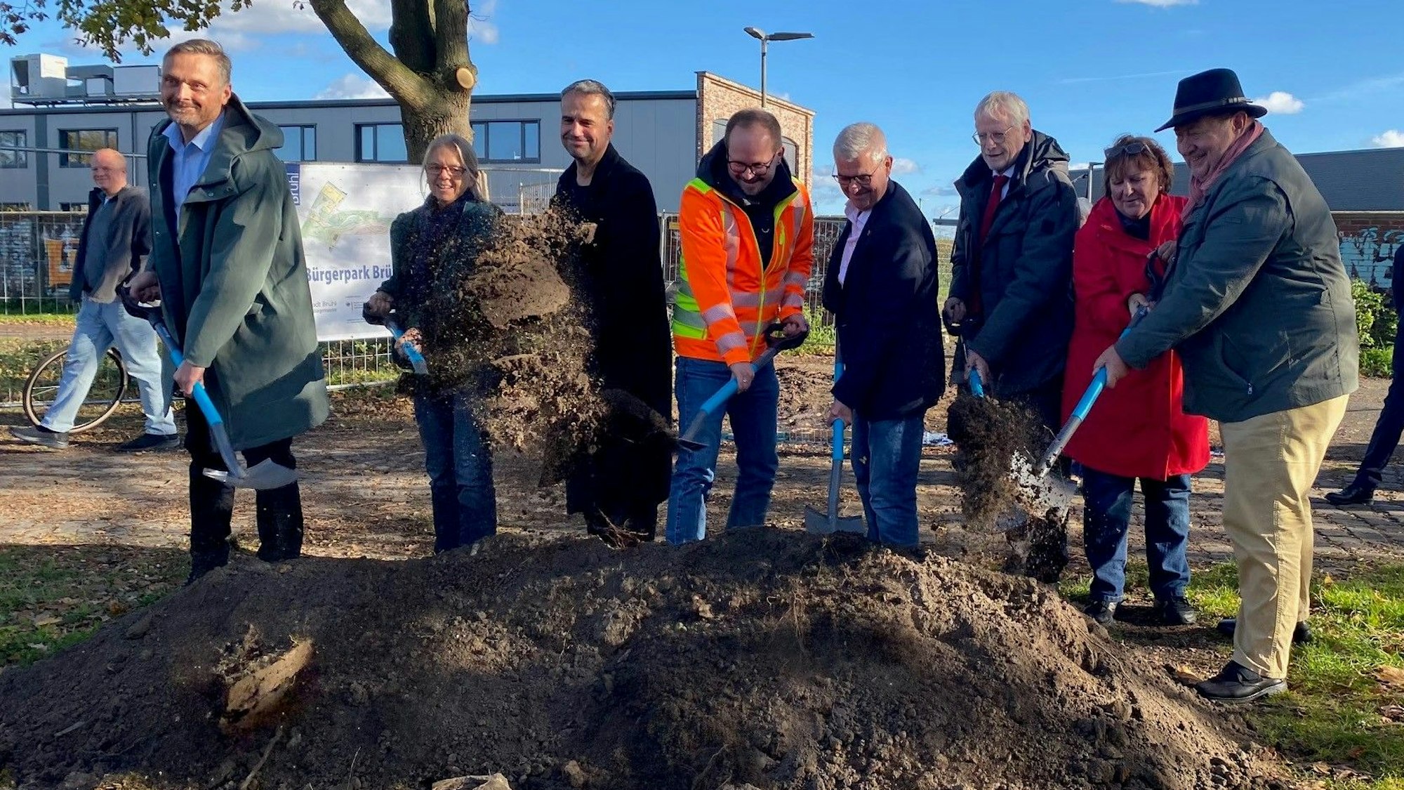 Zu sehen sind Männer und Frauen, die Spaten in den Händen halten und Erde schaufeln.