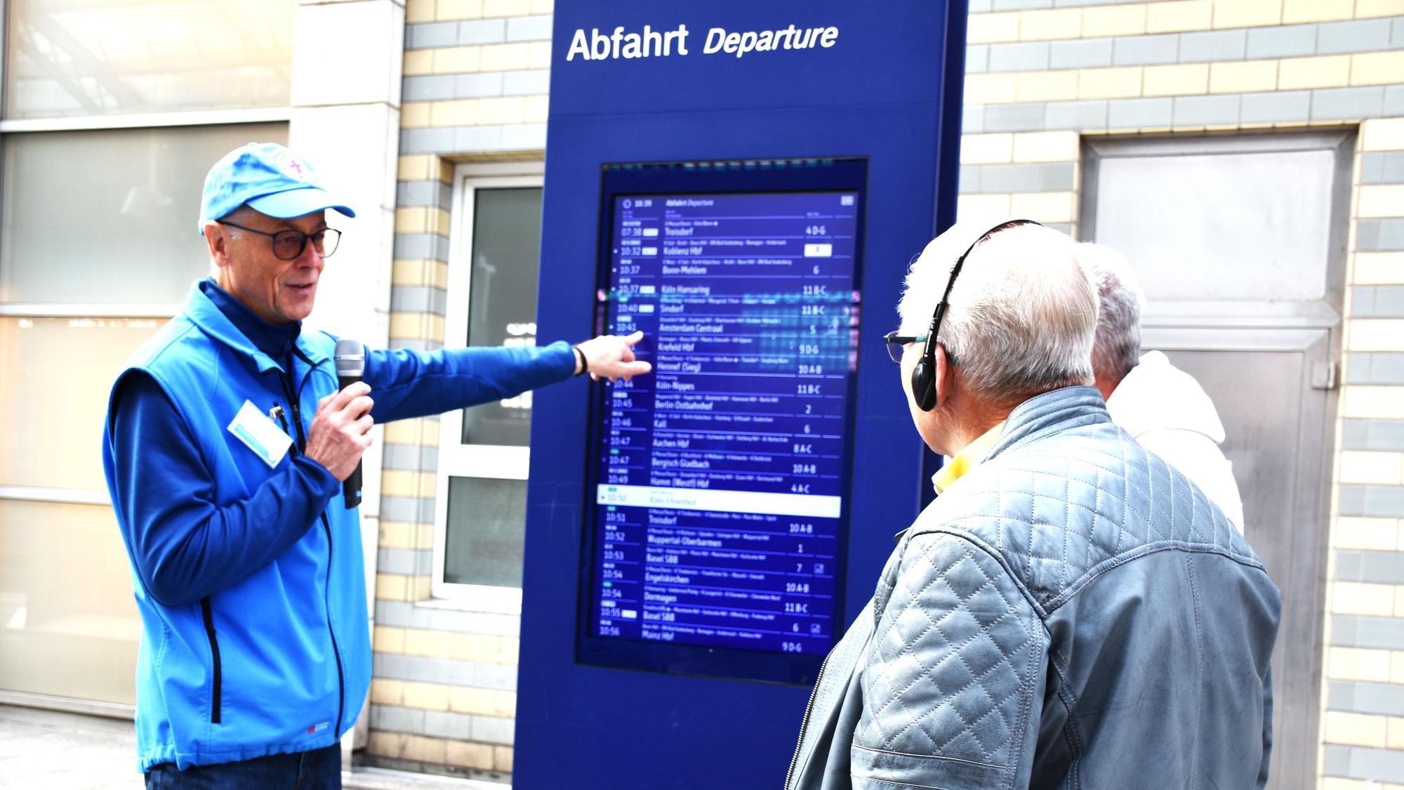 Ehrenamtliche der Bahnhofsmission führen Senioren durch den Kölner Hbf.