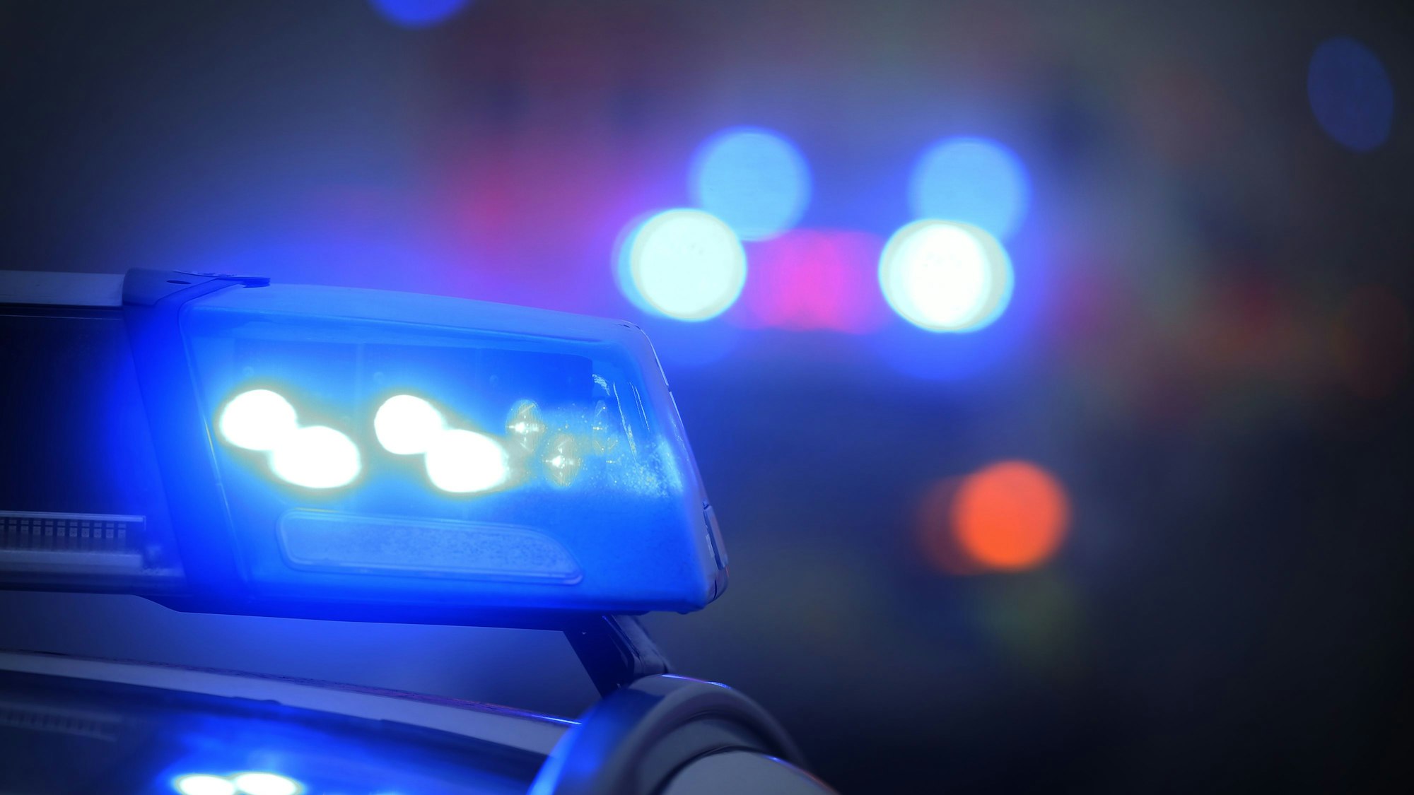 Ein Polizeiauto mit eingeschaltetem Blaulicht steht an einer Unfallstelle.