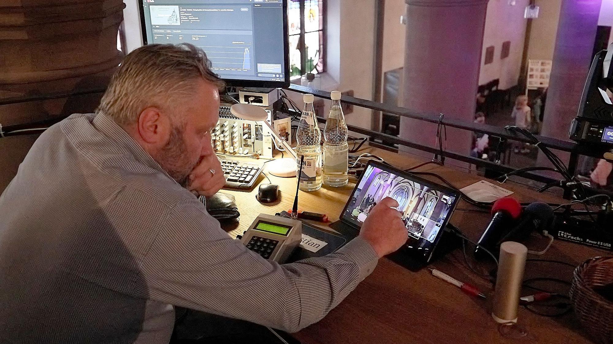 Auf der Empore der Kirche in Marmagen betrachtet ein Mann die Kamerabilder auf einem Tablet-Bildschirm.