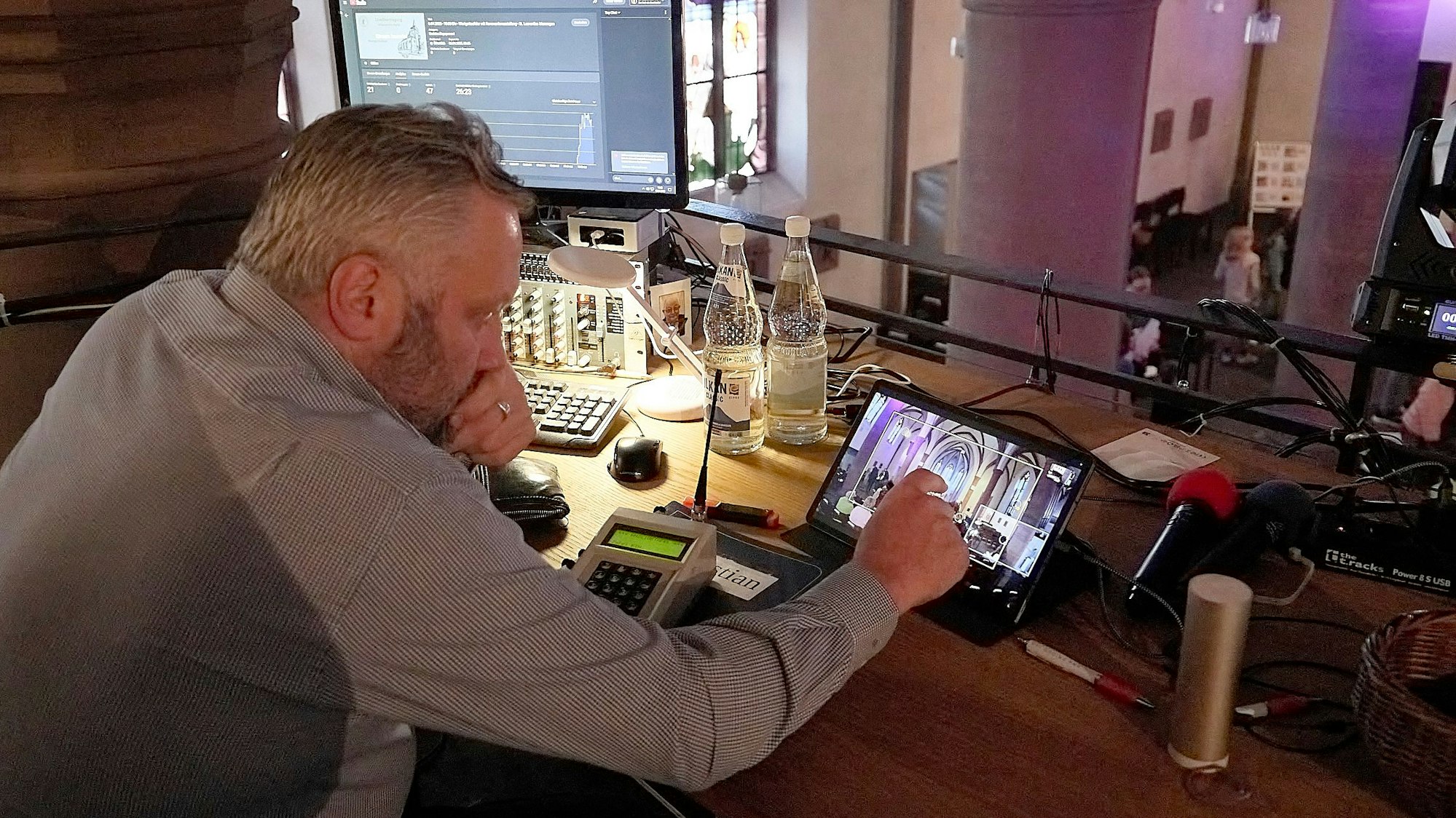 Auf der Empore der Kirche in Marmagen betrachtet ein Mann die Kamerabilder auf einem Tablet-Bildschirm.