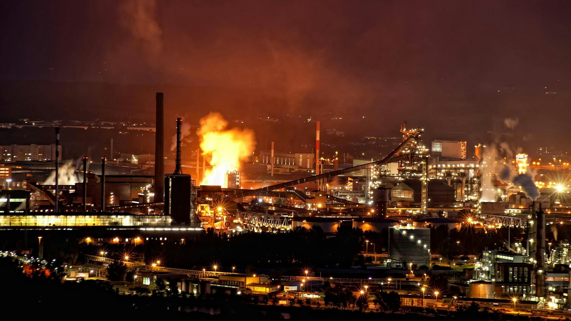 Industrieanlage bei Nacht mit Feuerschein. (Symbolbild)