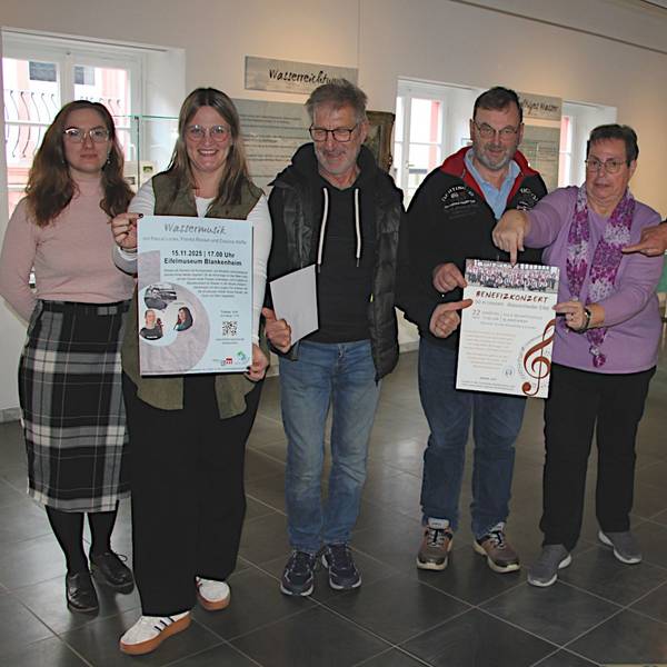 Sieben Personen stehen nebeneinander und lächeln in die Kamera. In den Händen halten sie Plakate, die für die Veranstaltungen werben.